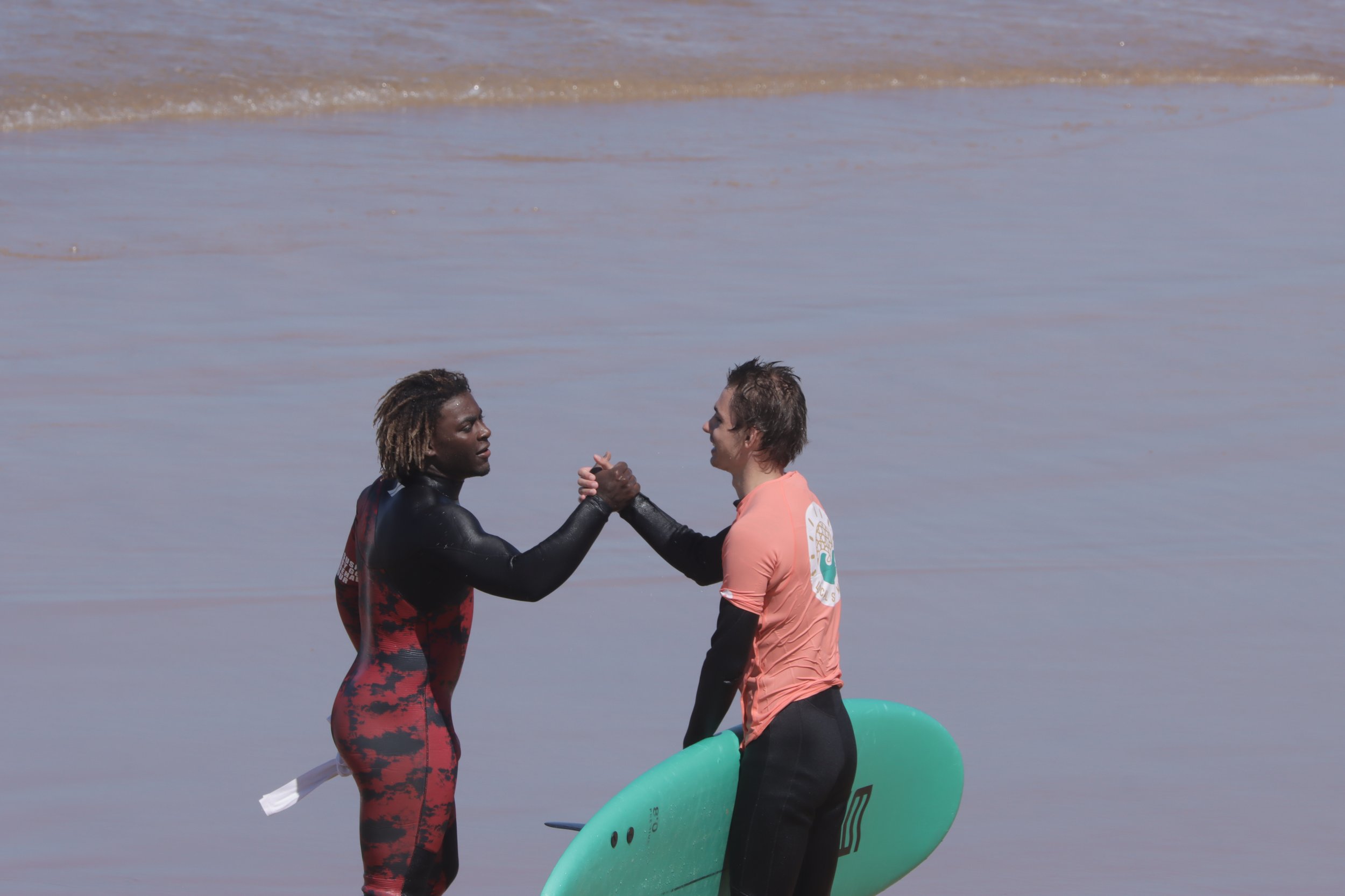Local Surf Maroc coach congratulating guest on a good surf in Taghazout Bay, Morocco.
