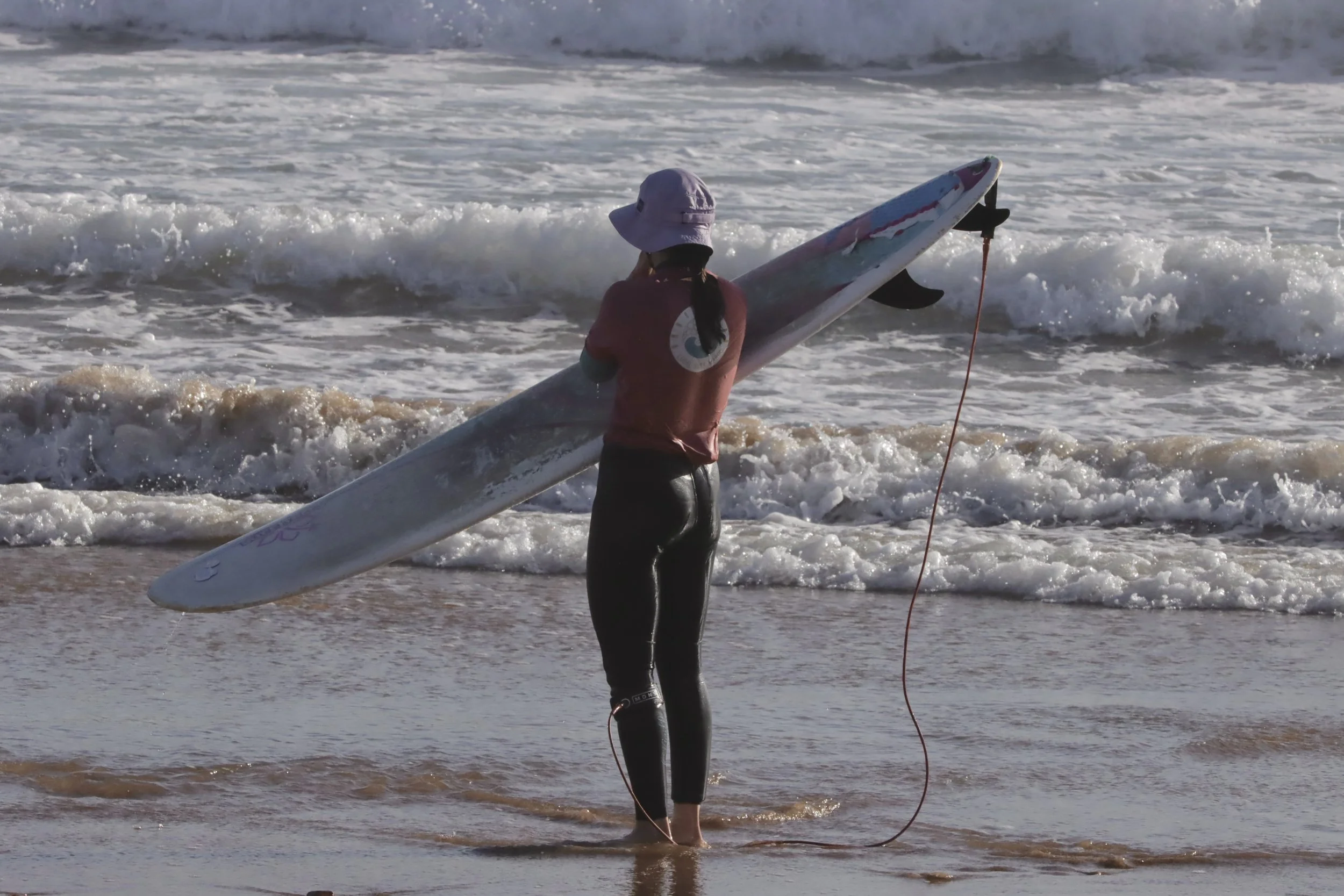 Intermediate surfer contemplating the waves after a sunset surf session, Taghazout, Morocco.