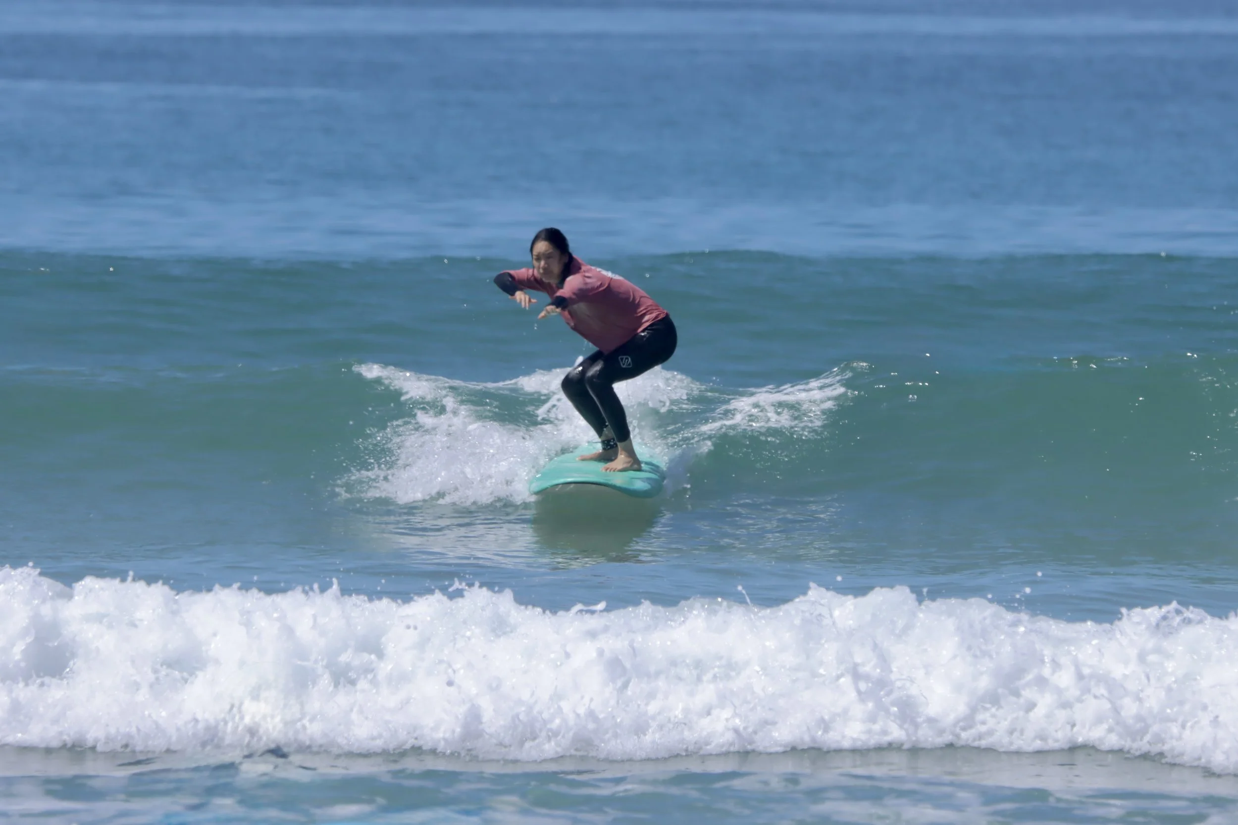 Beginner surfer catching small green waves at the end of her week with Local Surf Maroc, Taghazout, Morocco.