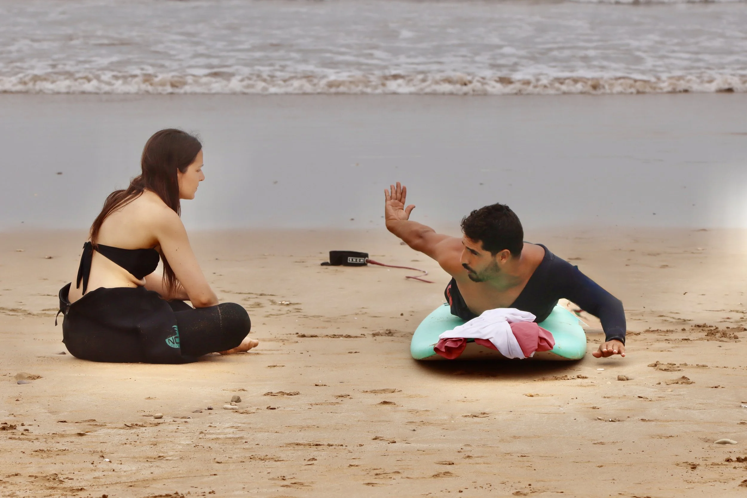 Surf coach demonstrating paddling and body positioning technique during structured beach training session in Taghazout, Morocco.