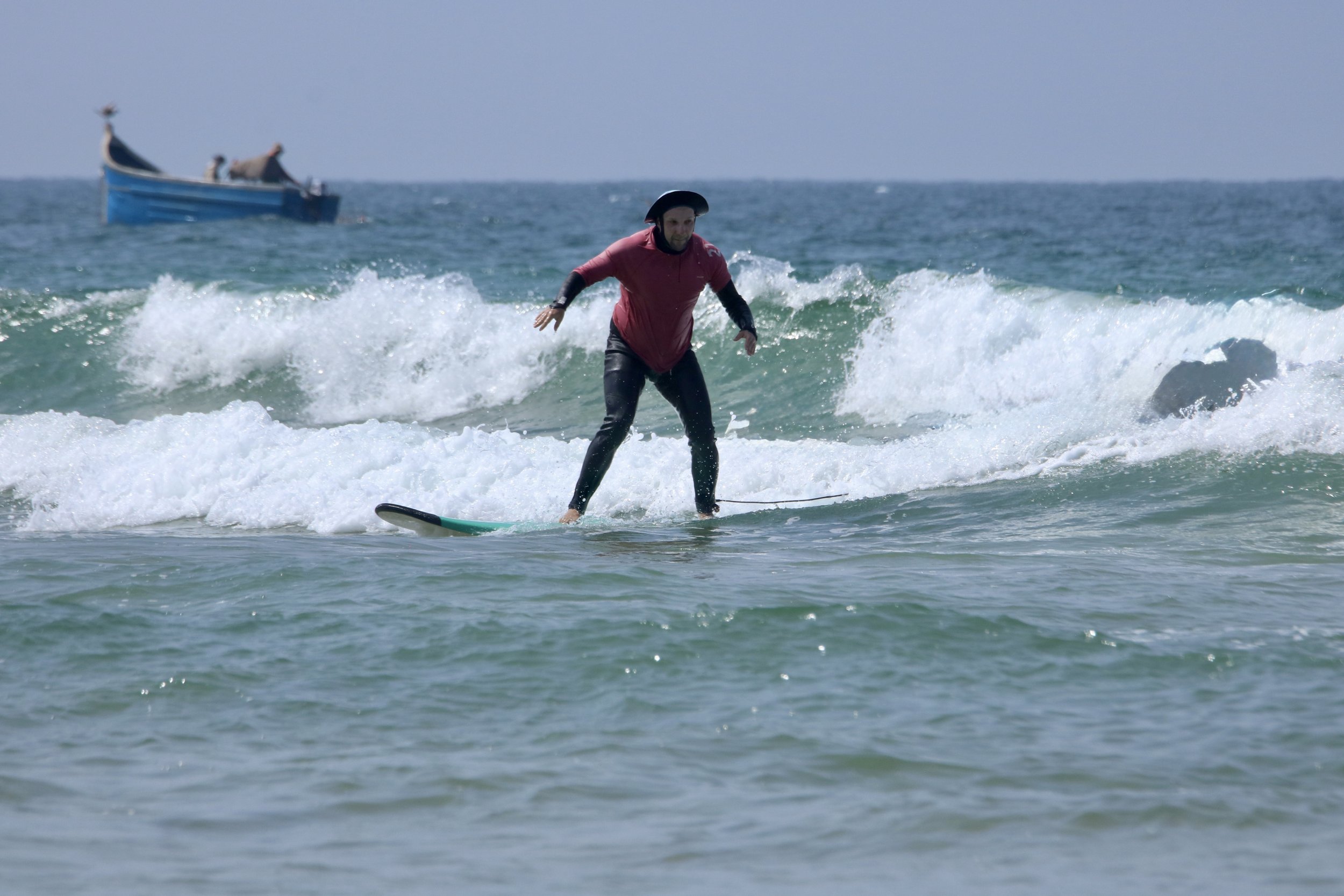 Beginner surfer surfing some small green waves with structured surf coaching in Taghazout, Morocco