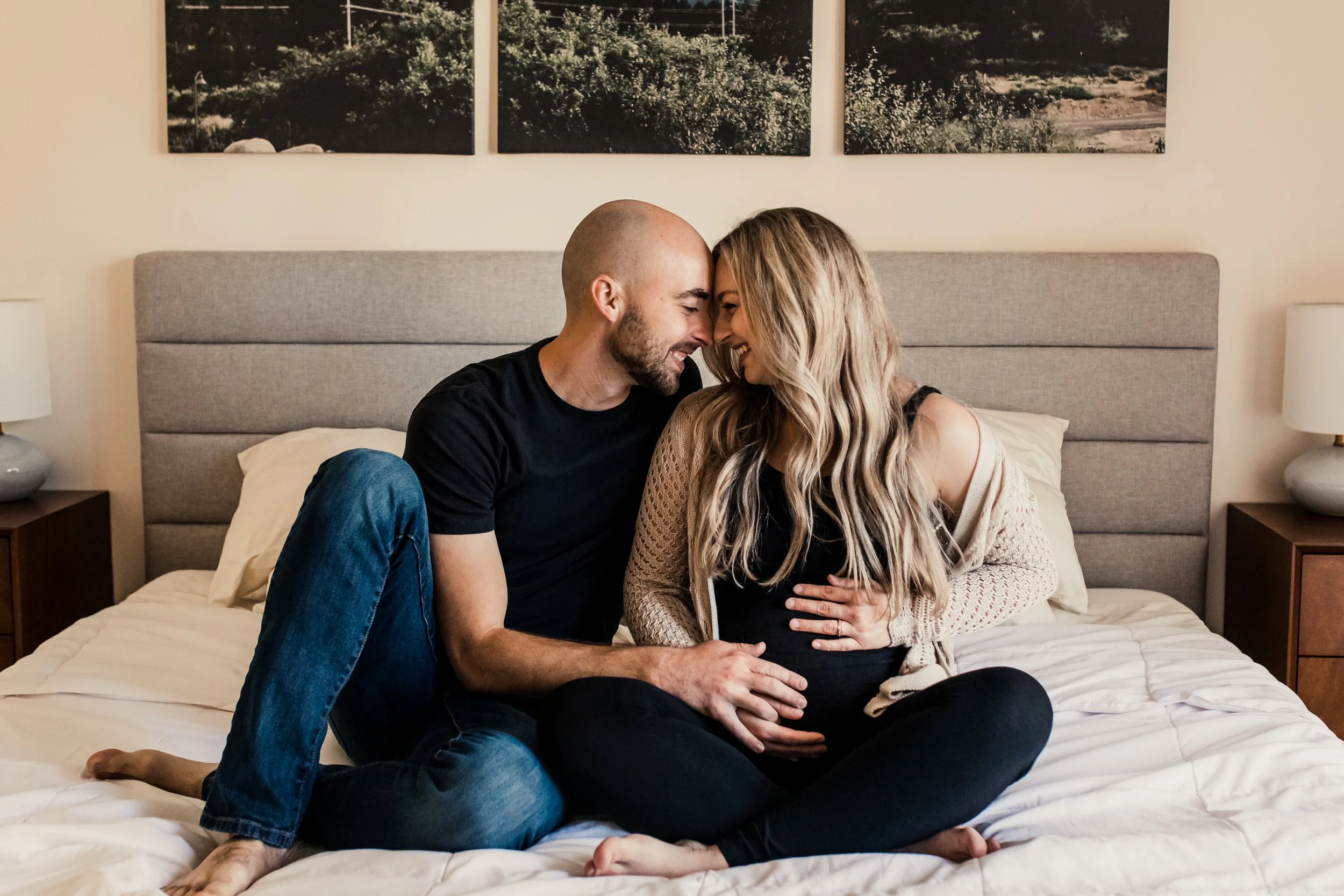 cozy, intimate maternity session in Spokane at home on south hill, mom and dad to-be sitting on bed nuzzling each other while holding pregnant belly