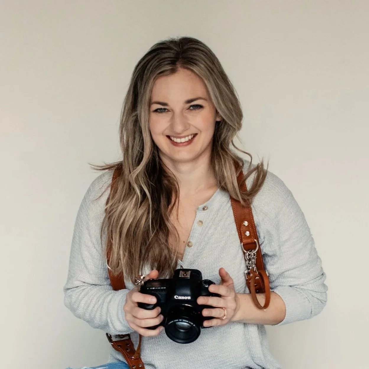 Spokane newborn photographer Britt Harvey holding a camera and posing for headshot
