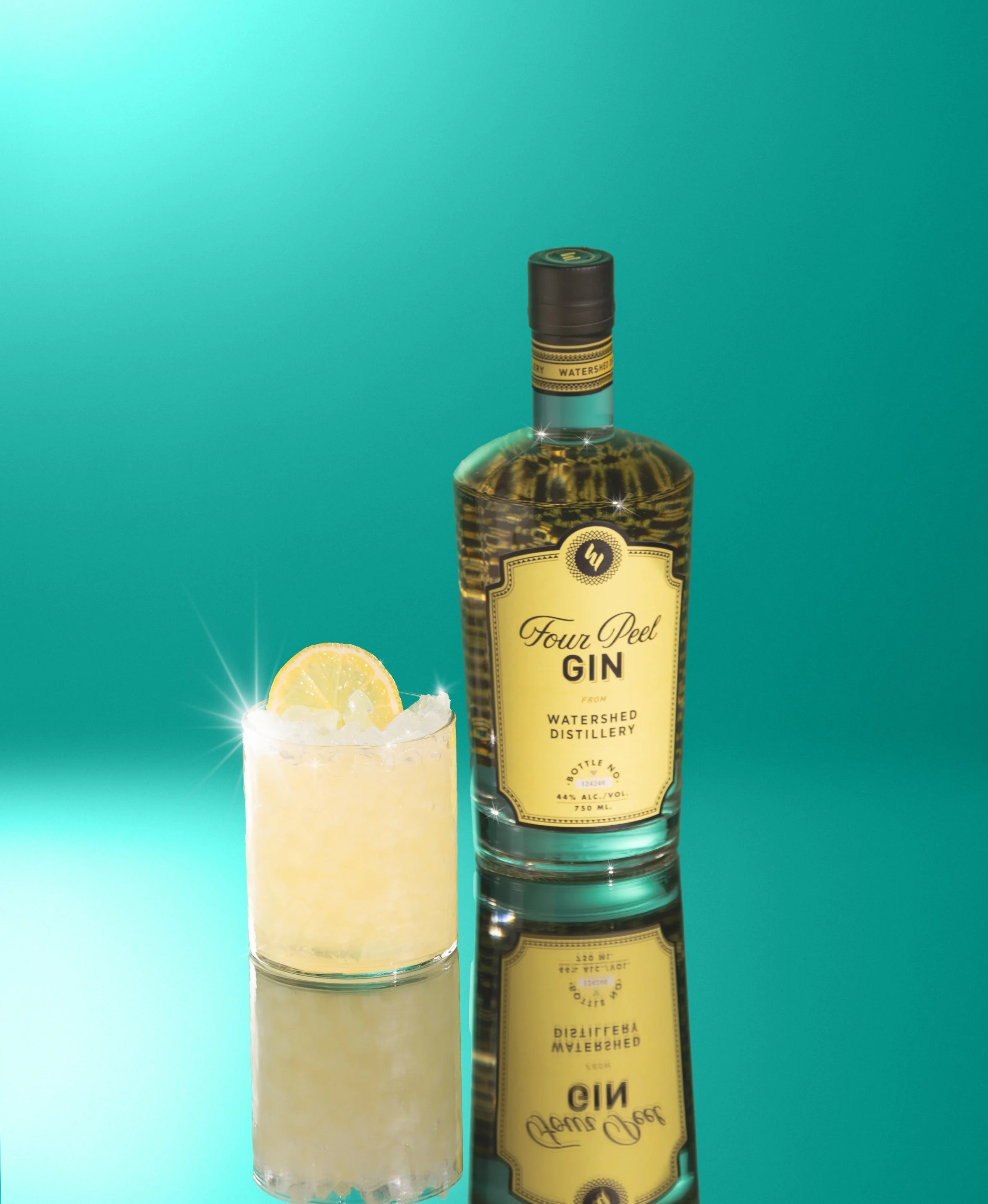 A bottle of Four Peel Gin from Watershed Distillery next to a lemon wedge in a glass of ice with lemon slice garnish, set against a teal background.