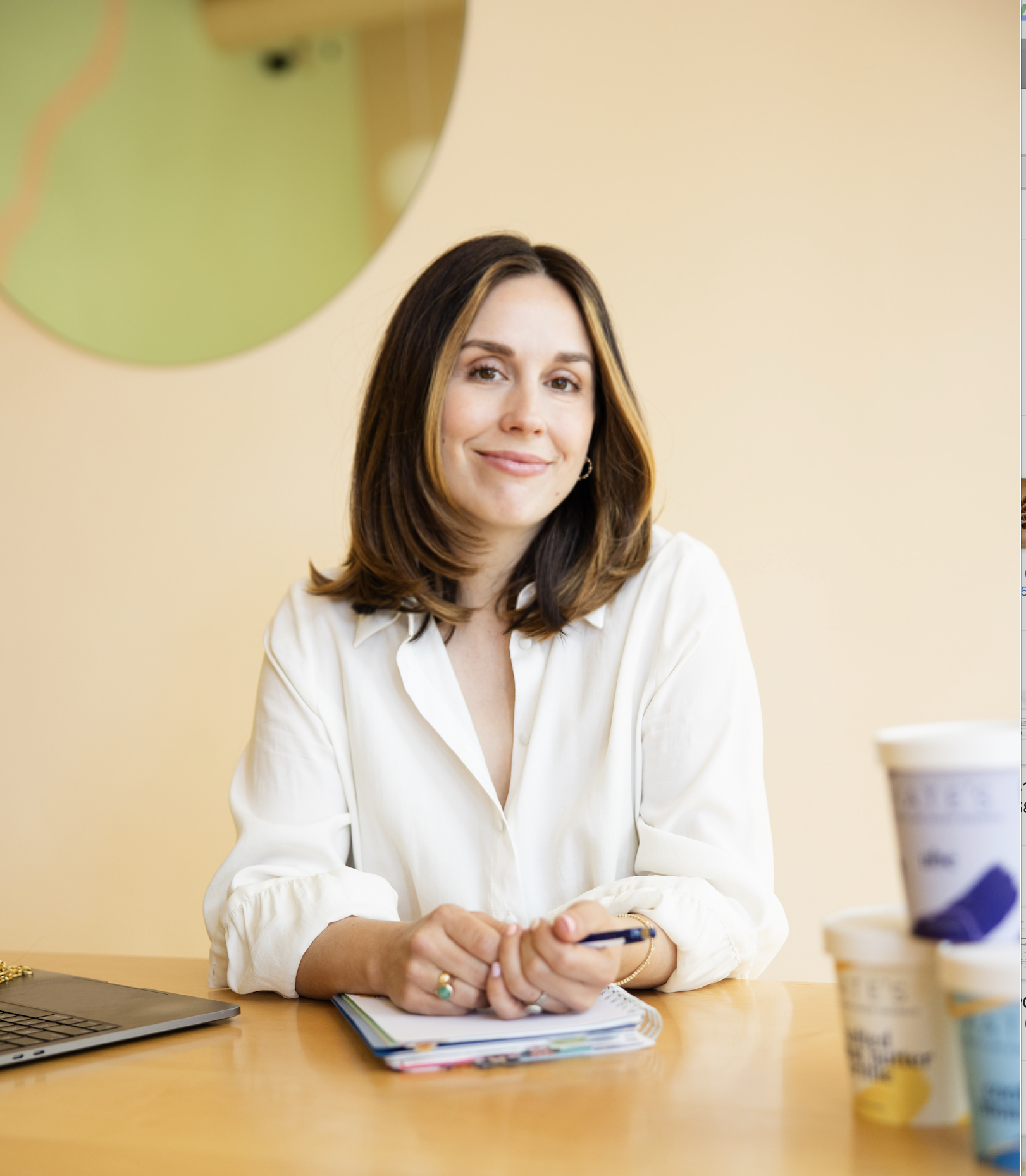Kate Williams, founder of Kate's Waffle Cones, smiling for the camera in front of ice cream and a notepad
