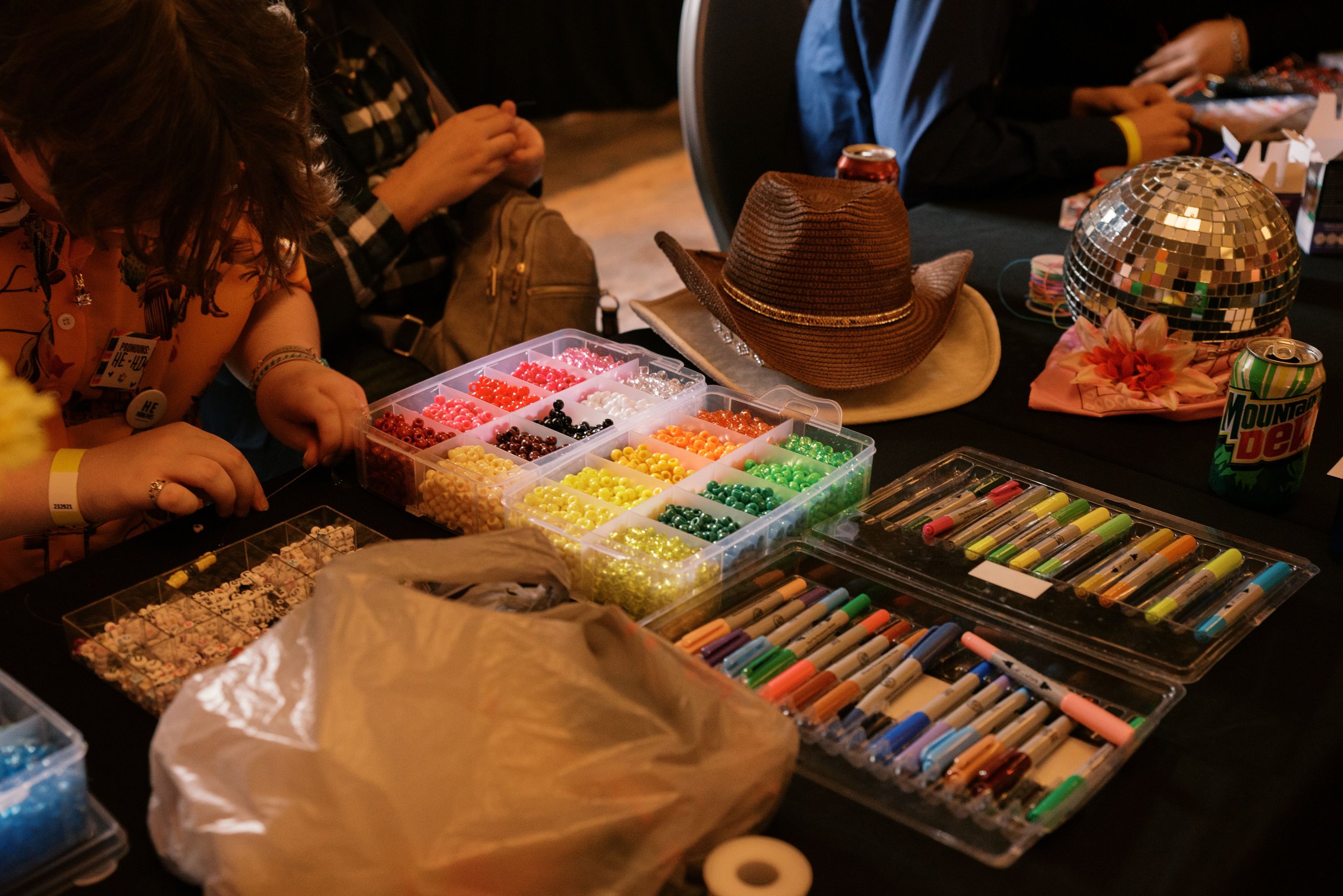 arts and craft supplies laid out on a table while youth gather around to make crafts