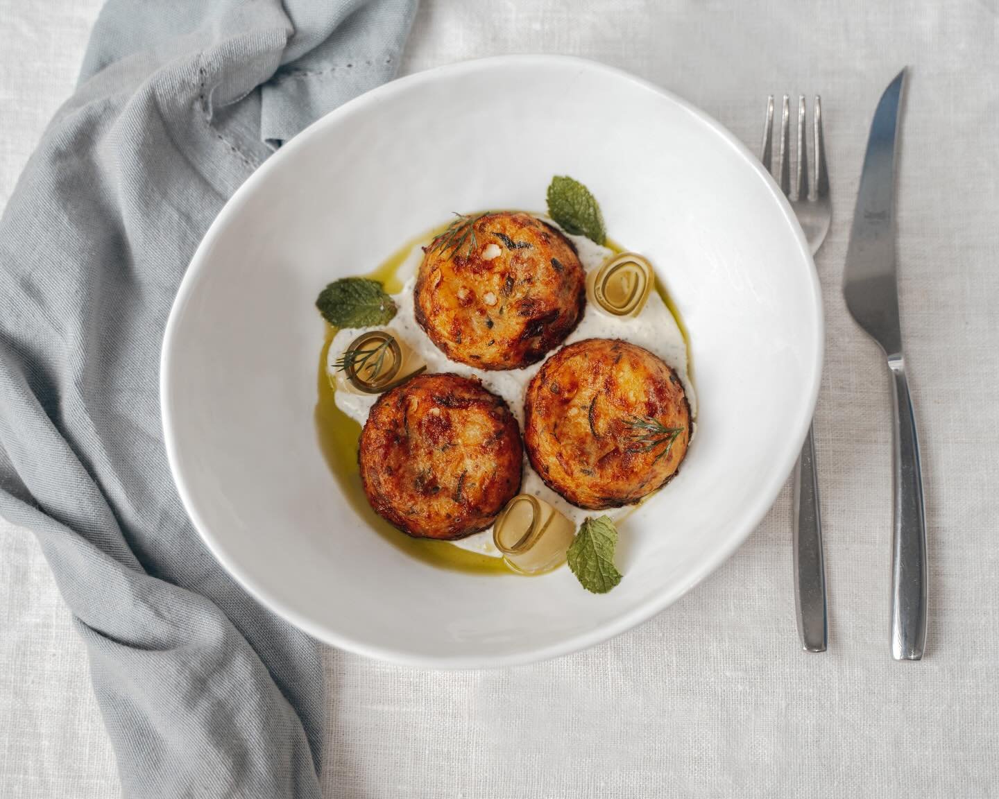 Kolokithokeftedes reci&eacute;n hechas, doradas por fuera y suaves por dentro.
Croquetas de Calabac&iacute;n, hierbas frescas y ese punto griego que funciona siempre en la mesa, ya sea para compartir o para empezar sin prisas.
Un cl&aacute;sico senci