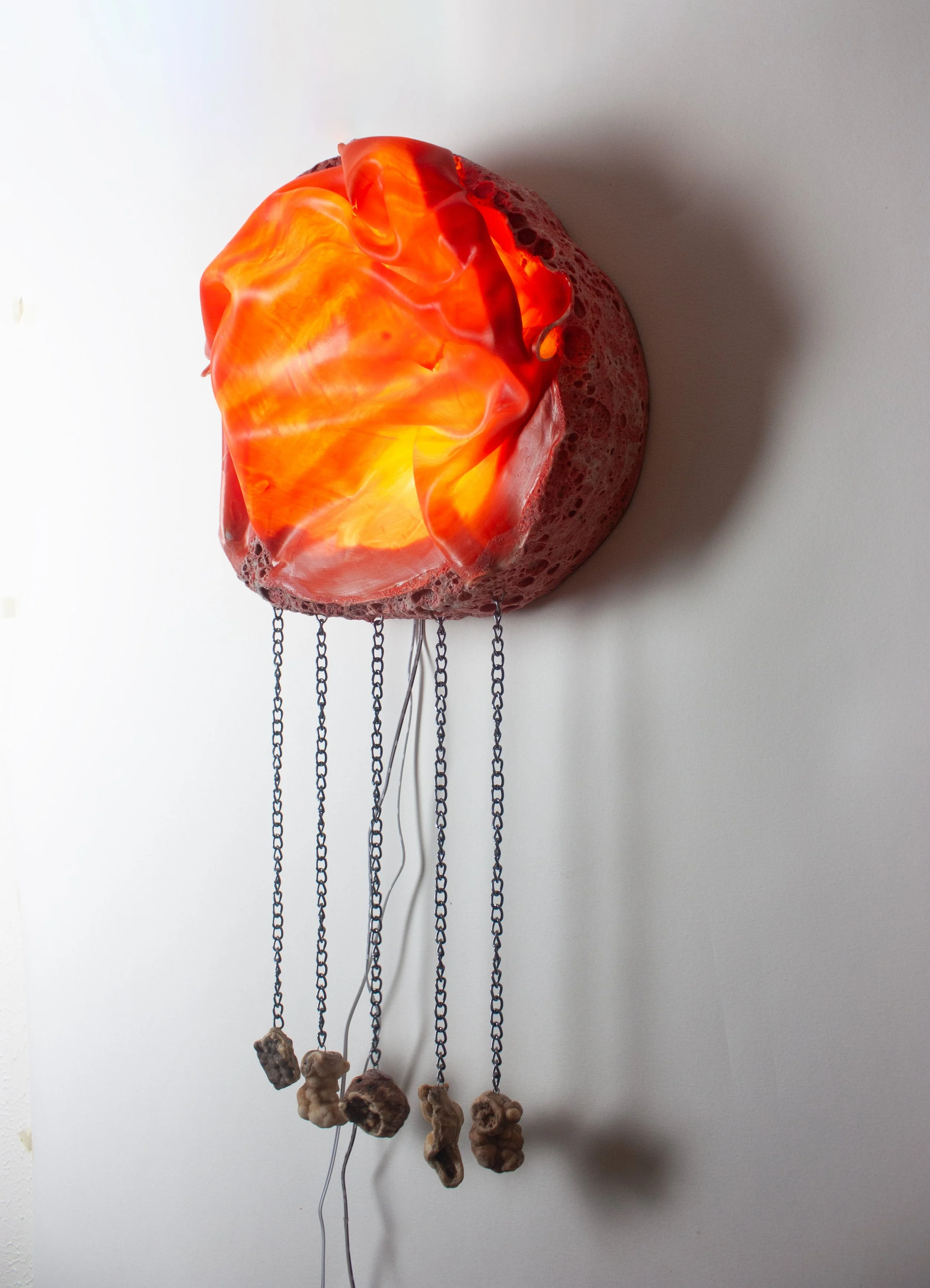 "Magma," 2025. Translucent porcelain, river stones, chain, stoneware, glaze, lighting. 