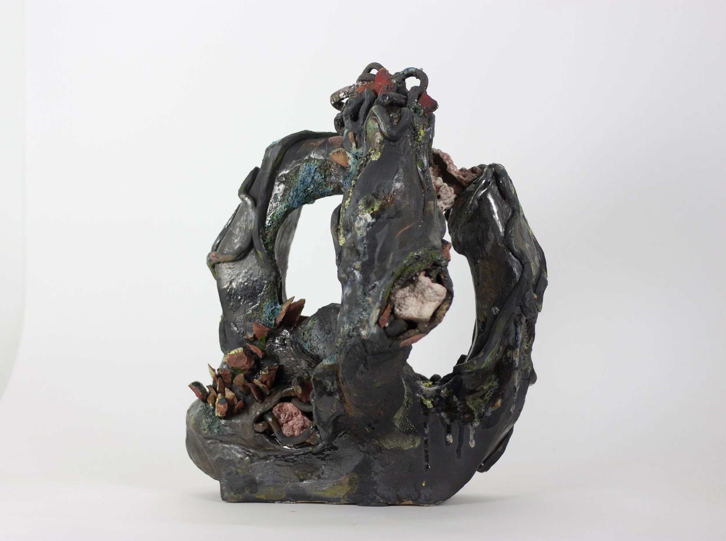 "Age undoes itself/and plays the Ouroboros" 2023. Black clay, shards of exploded bisque soaked in red pigment, Ozark rocks, Houston sand, gravel, glaze. 23 x 17 x 11 inches.
