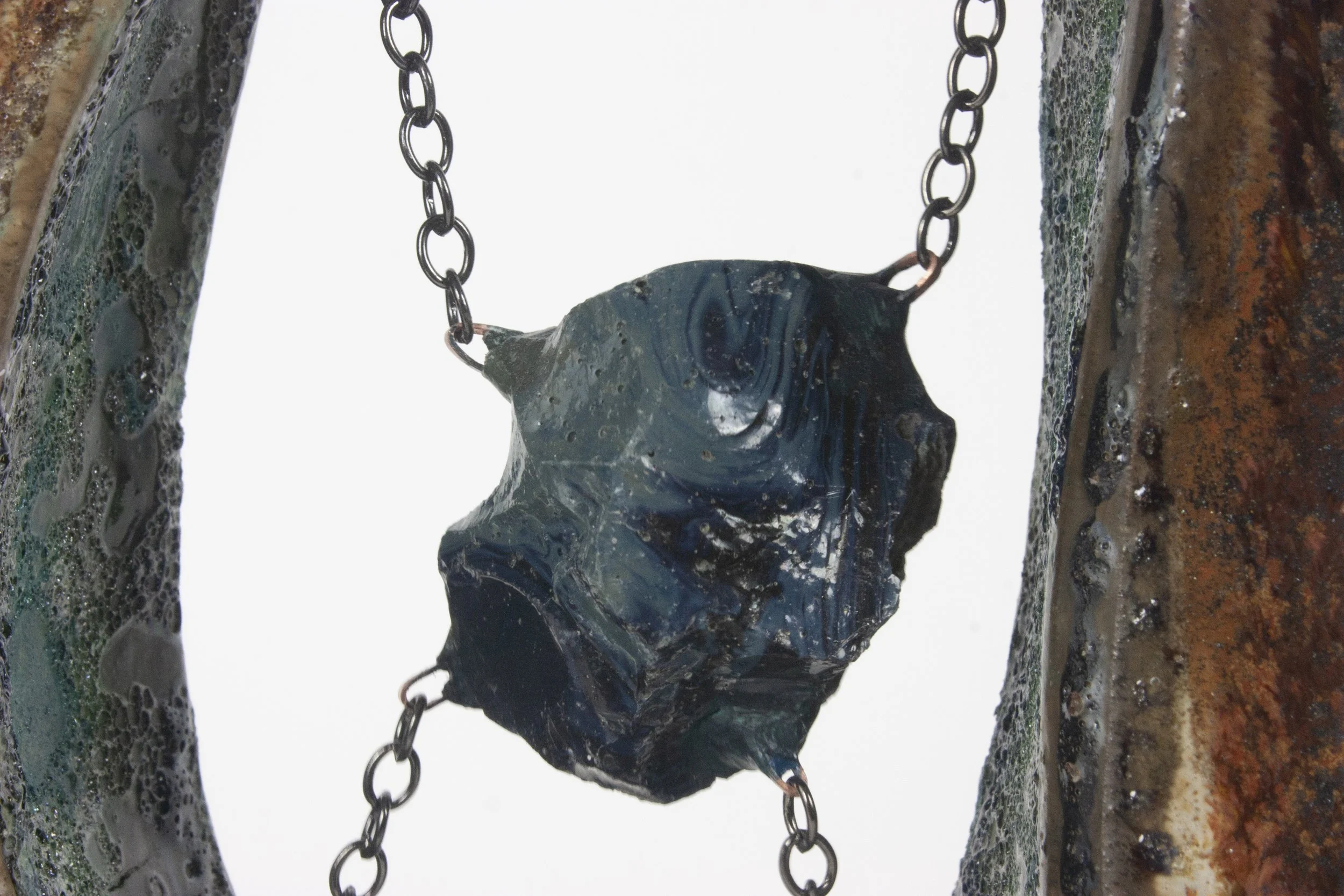 "Slag," 2023. Slag glass from the National Building Arts Center in Sauget, IL, chain, crushed steel glaze, ceramic, apoxie clay. 8 x 4.5 x 1.5 inches.