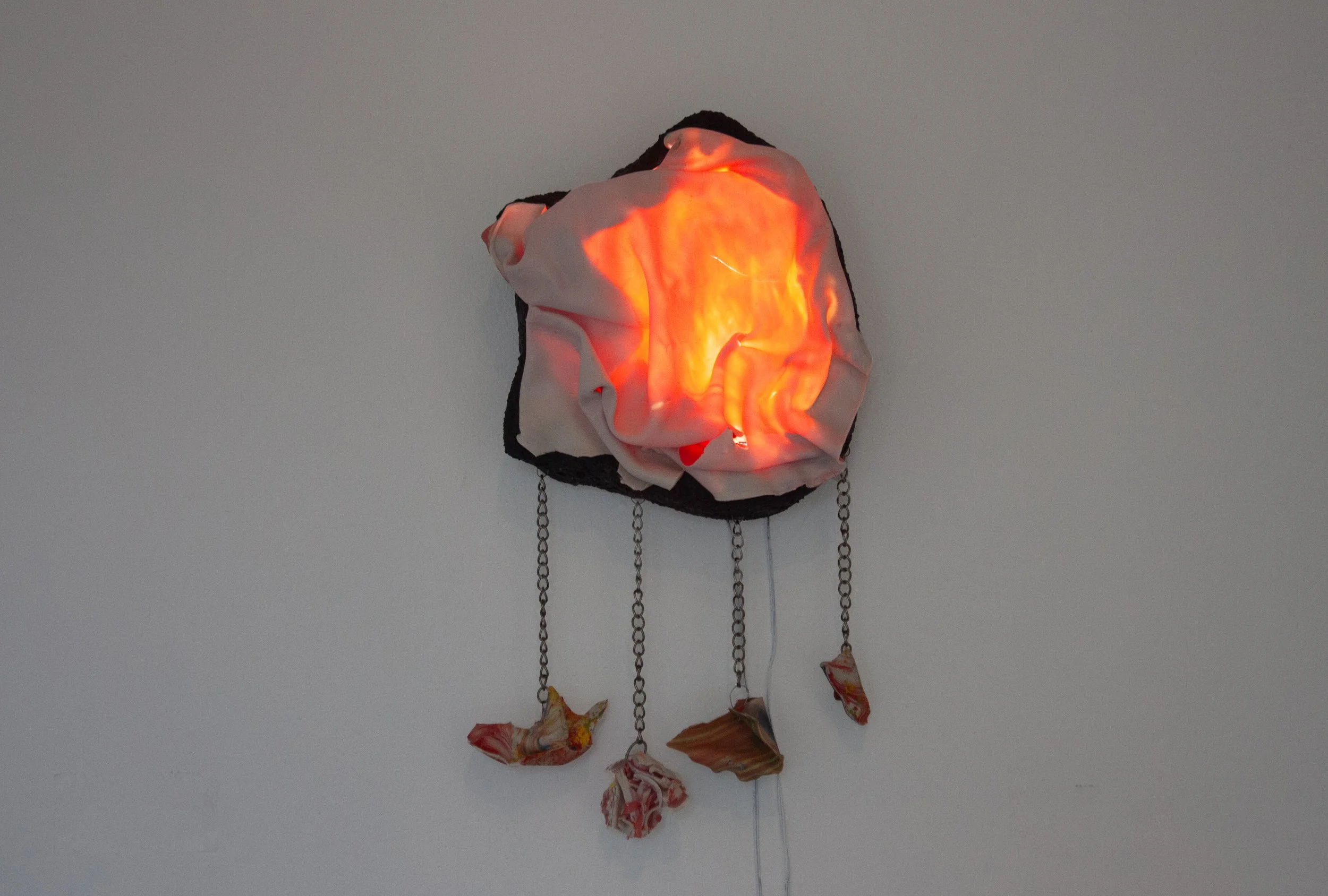 "Molten," 2025. Translucent porcelain, shards from a piece dropped on the ground, chain, stoneware, glaze, lighting. 