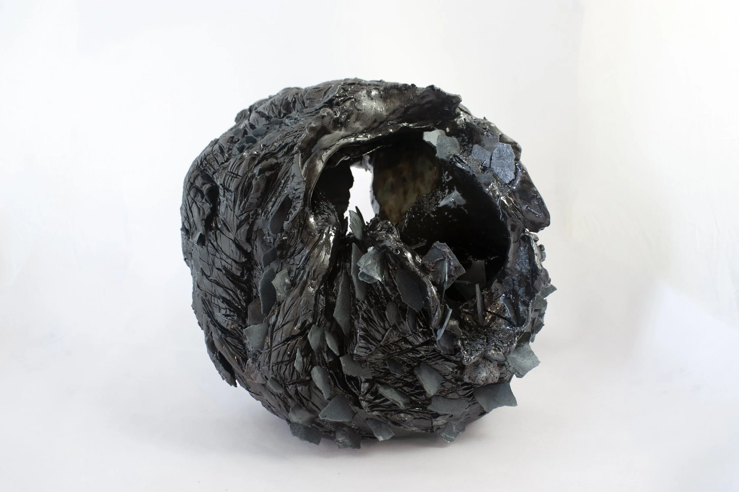 "Nucleus," 2023. Steel fragments, serrated black stoneware, crushed steel glaze.