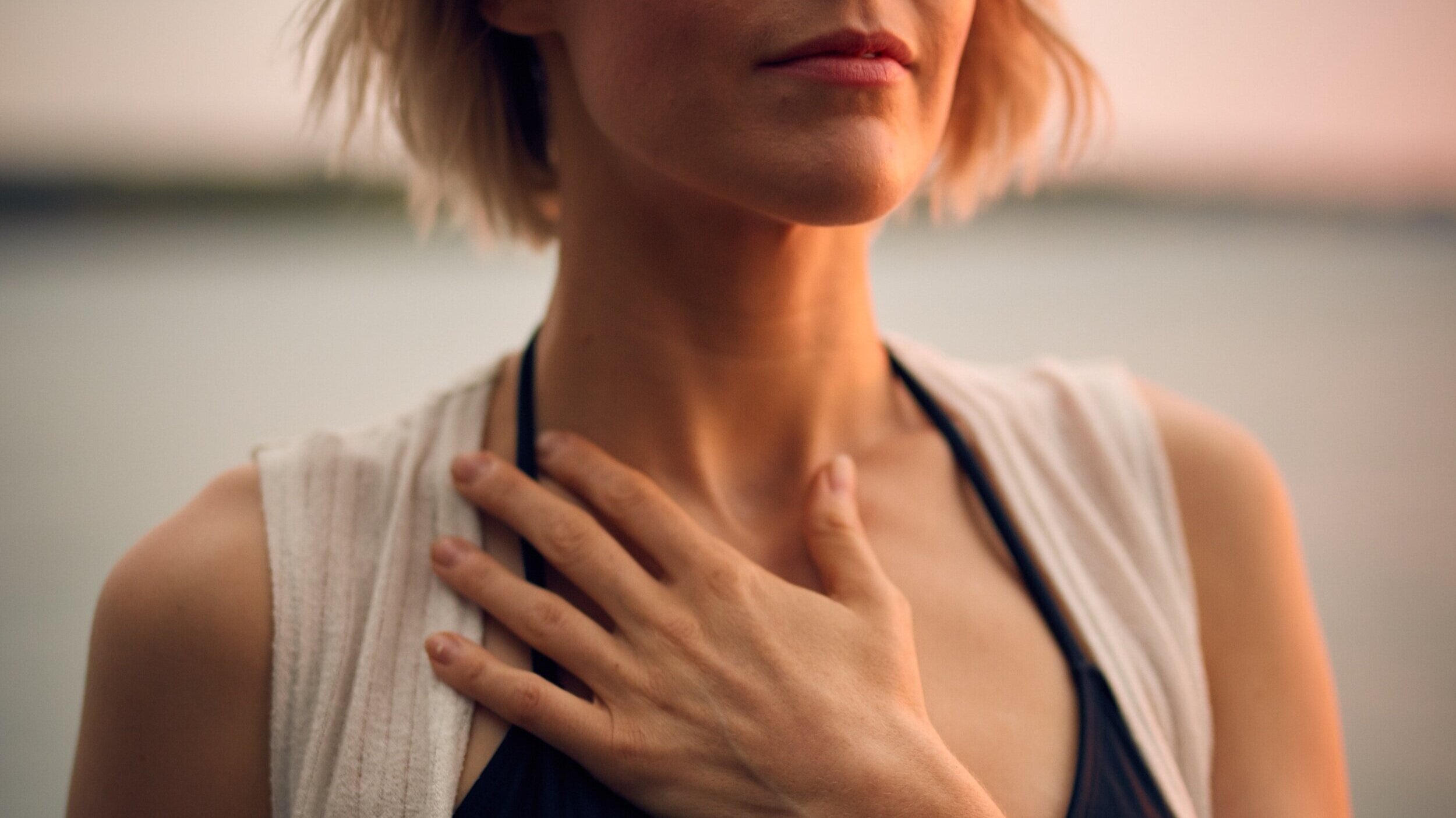  Close-up photo of woman with her hand on her collarbone. 