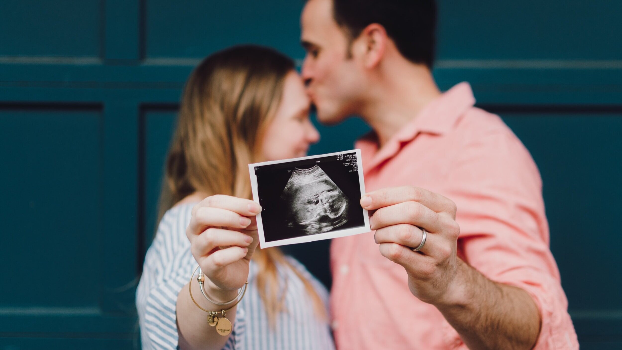  Photo of woman and man holding up an ultrasound picture of a baby. 