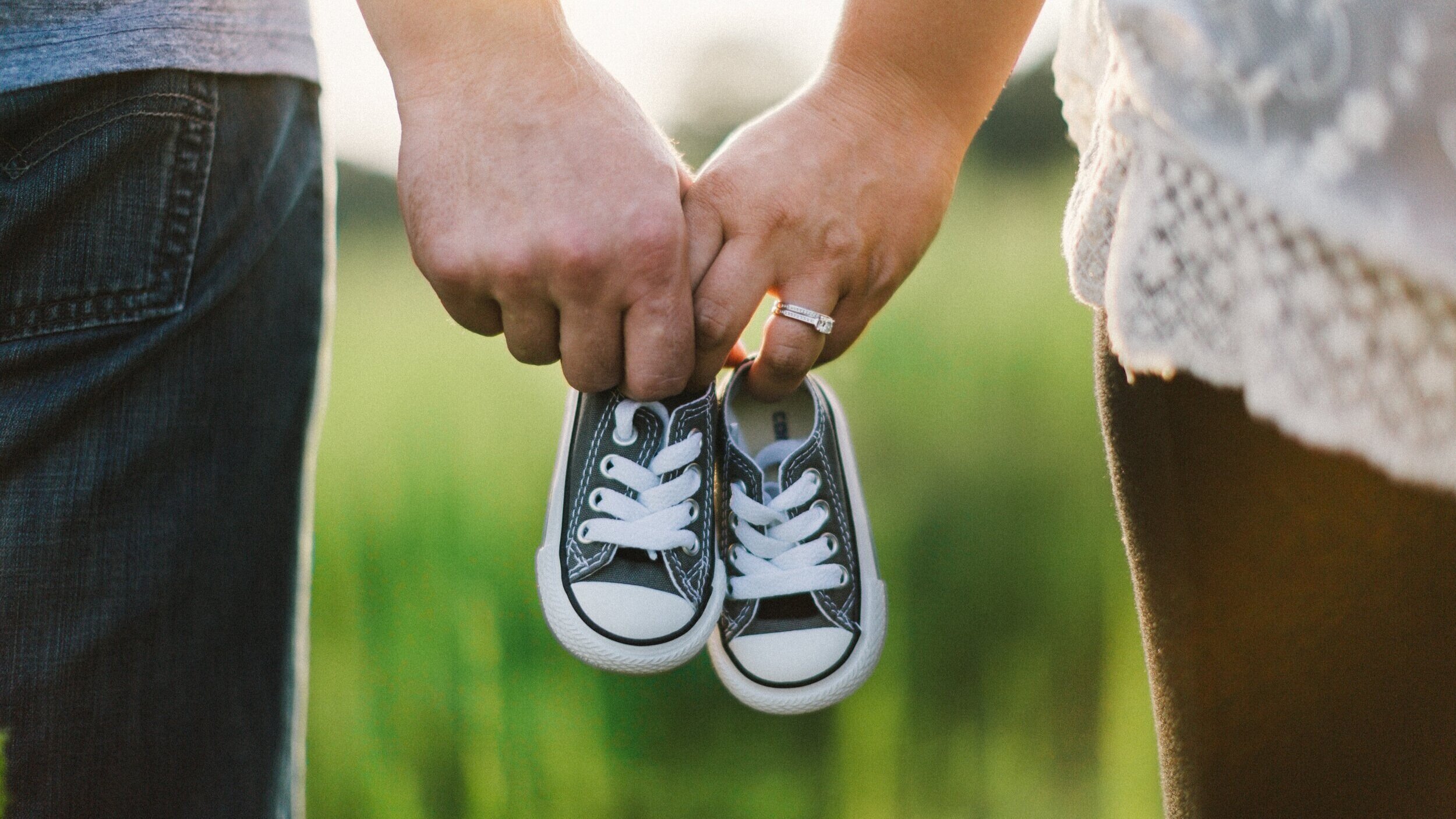  Photo of woman and man holding hands and tiny pair of sneakers. 