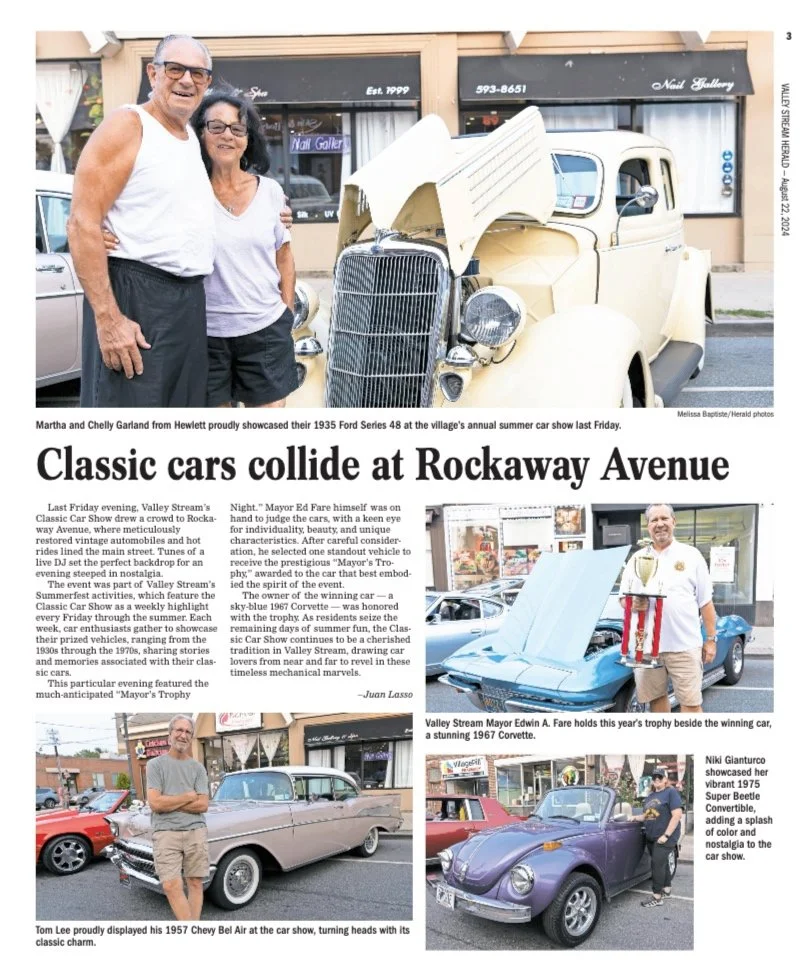 Two smiling adults, a man and a woman, standing next to a vintage yellow 1935 Ford Model 48 car at a car show on Rockaway Avenue, with storefronts in the background.