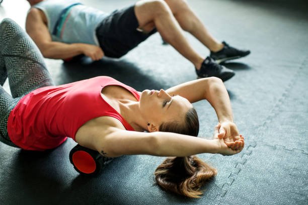  Young woman doing pilates exercise on floor at gym class 