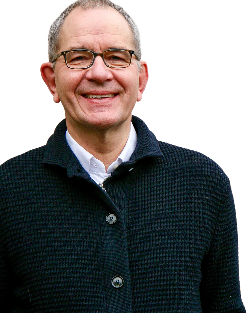 Ein Mann mit Brille, grauem Haar, lächelnd, trägt eine dunkle Strickjacke und ein weißes Hemd.