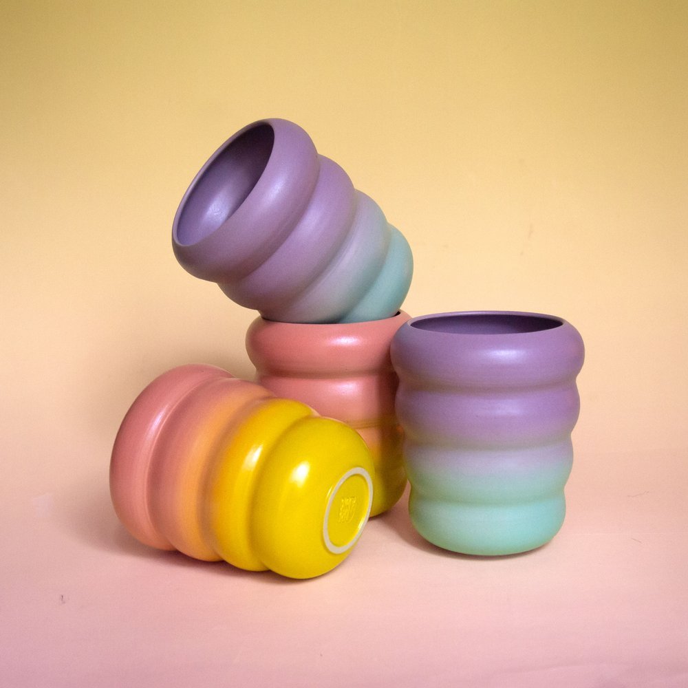 four ceramic cups in colorful gradients in a wavy design