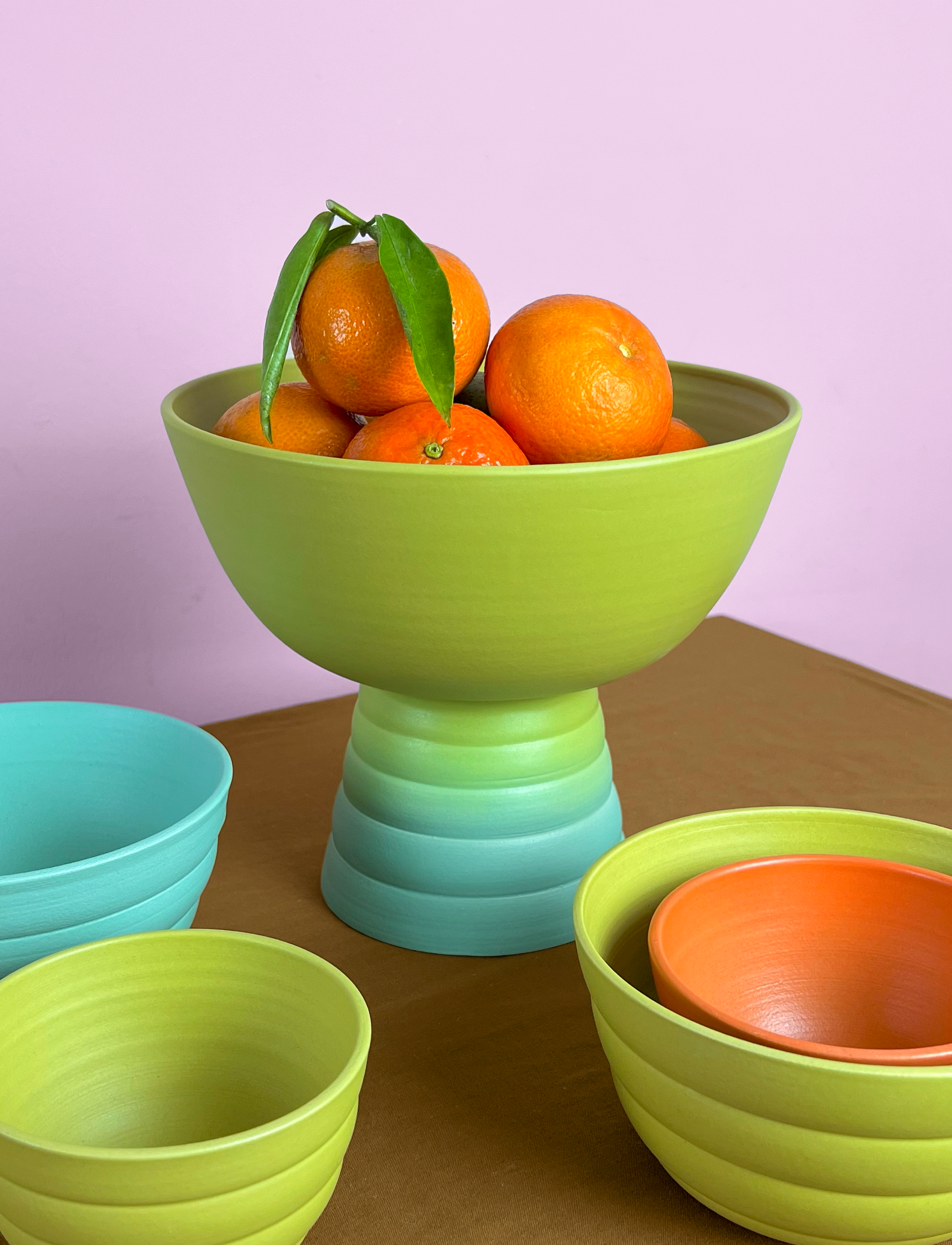 A still life of on of Marilyne Blais' memphis pedestal fruit bowl filled with oranges.