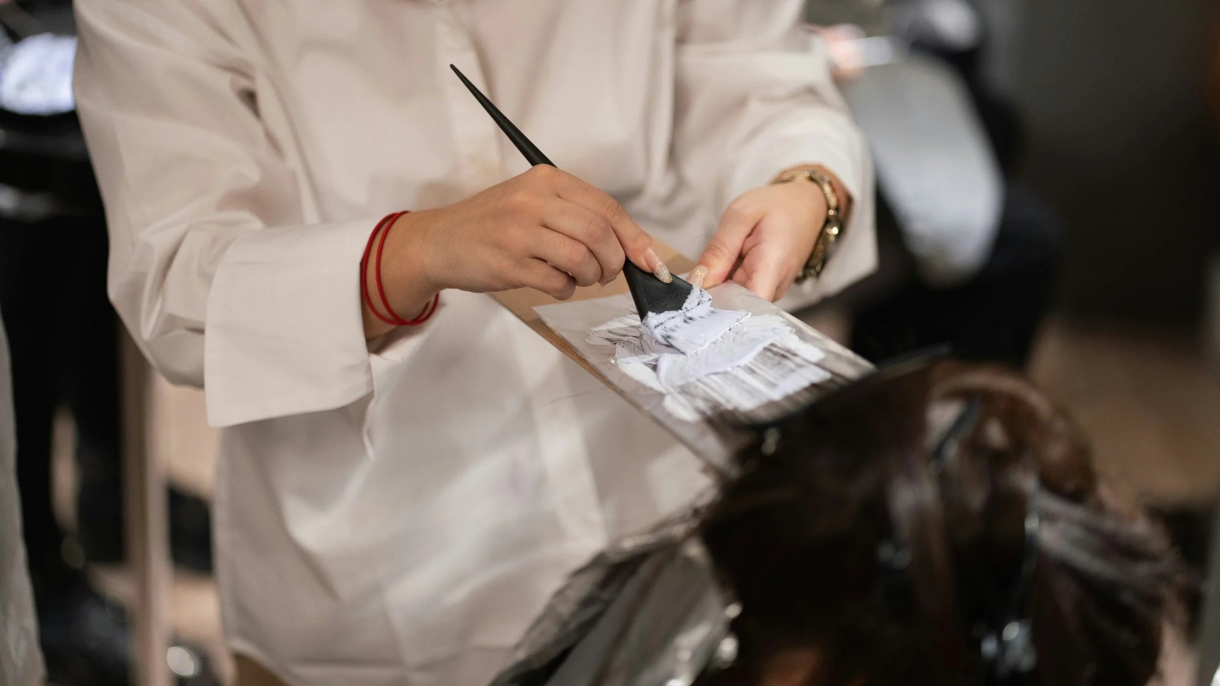 A colorist hand-painting dimensional balayage hair highlights at Street Salon Back Bay in Boston.
