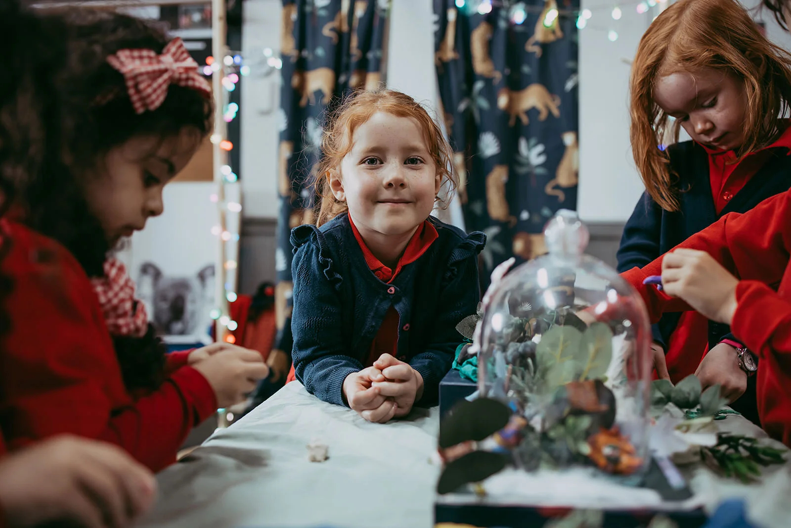 Children decorating a holiday table with a girl in the center smiling at the camera.