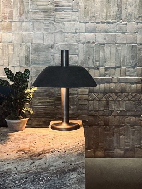 A black lamp sits on a stone table in front of a stone wall in the 1 West Hollywood Hotel.