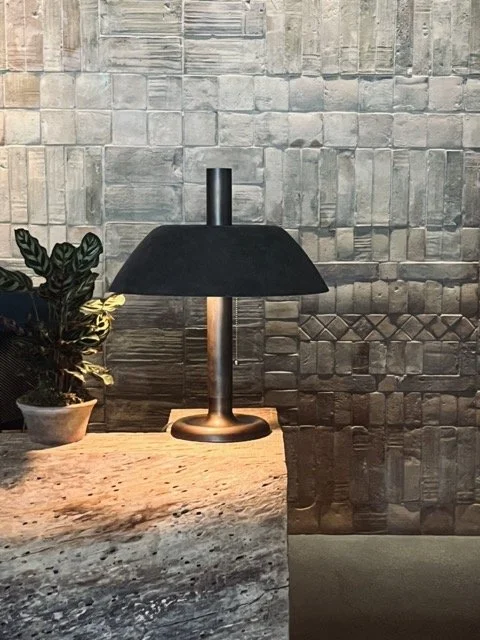 A black lamp sits on a stone table in front of a stone wall in the 1 West Hollywood Hotel.