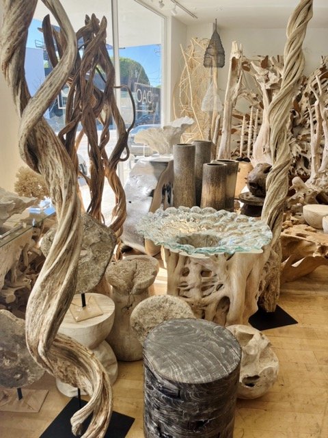 Teak root tables and other natural wood art pieces are displayed at DOA.