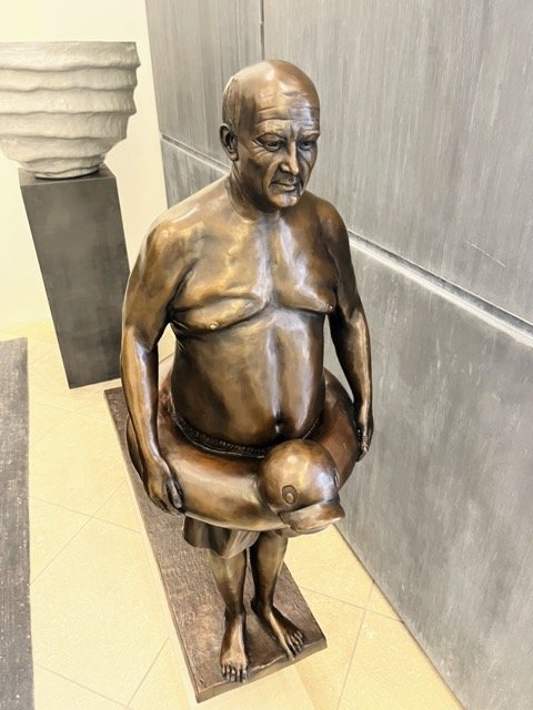 A bronze statue of a man in swim trunks with a duck flotation tube around his waist at the Perennials and Sutherland showroom at the West Hollywood Design District.