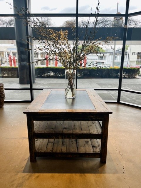 A coffee table with a vase and greenery sits in front of the window and the James Perse showroom in West Hollywood Design District.
