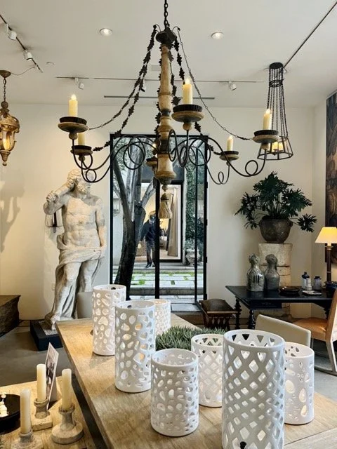 A stone statue of a man in the background of white candle holders on a table at Formations in West Hollywood.