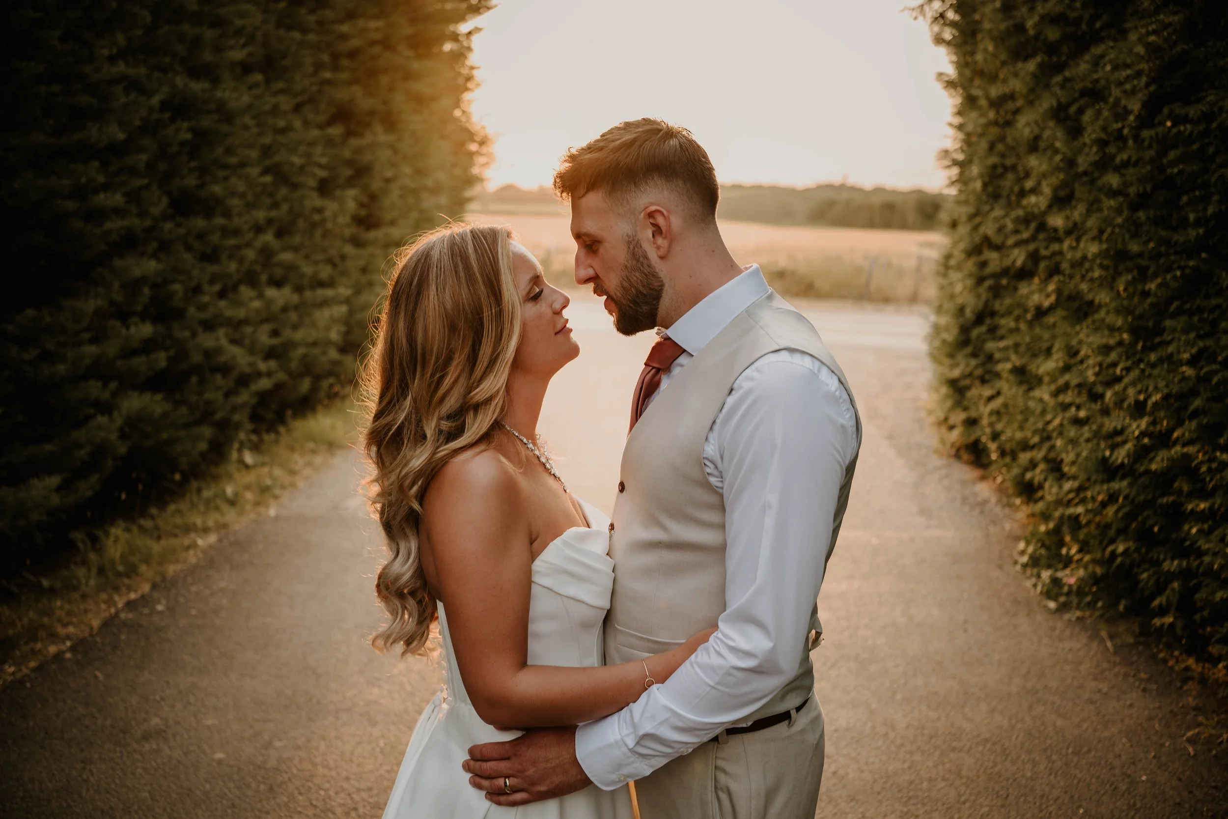 Bride and groom facing each other as the sun sets at Old Kent Barn