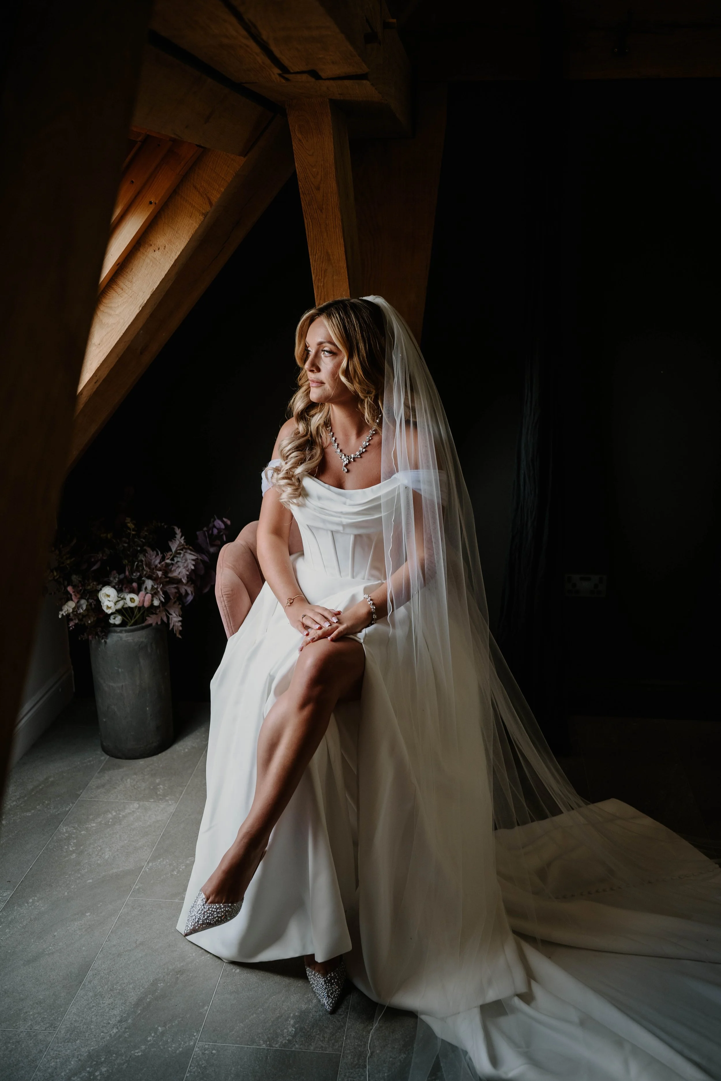 bride sitting on a stall looking out the window in the prep area at Old Kent Barn