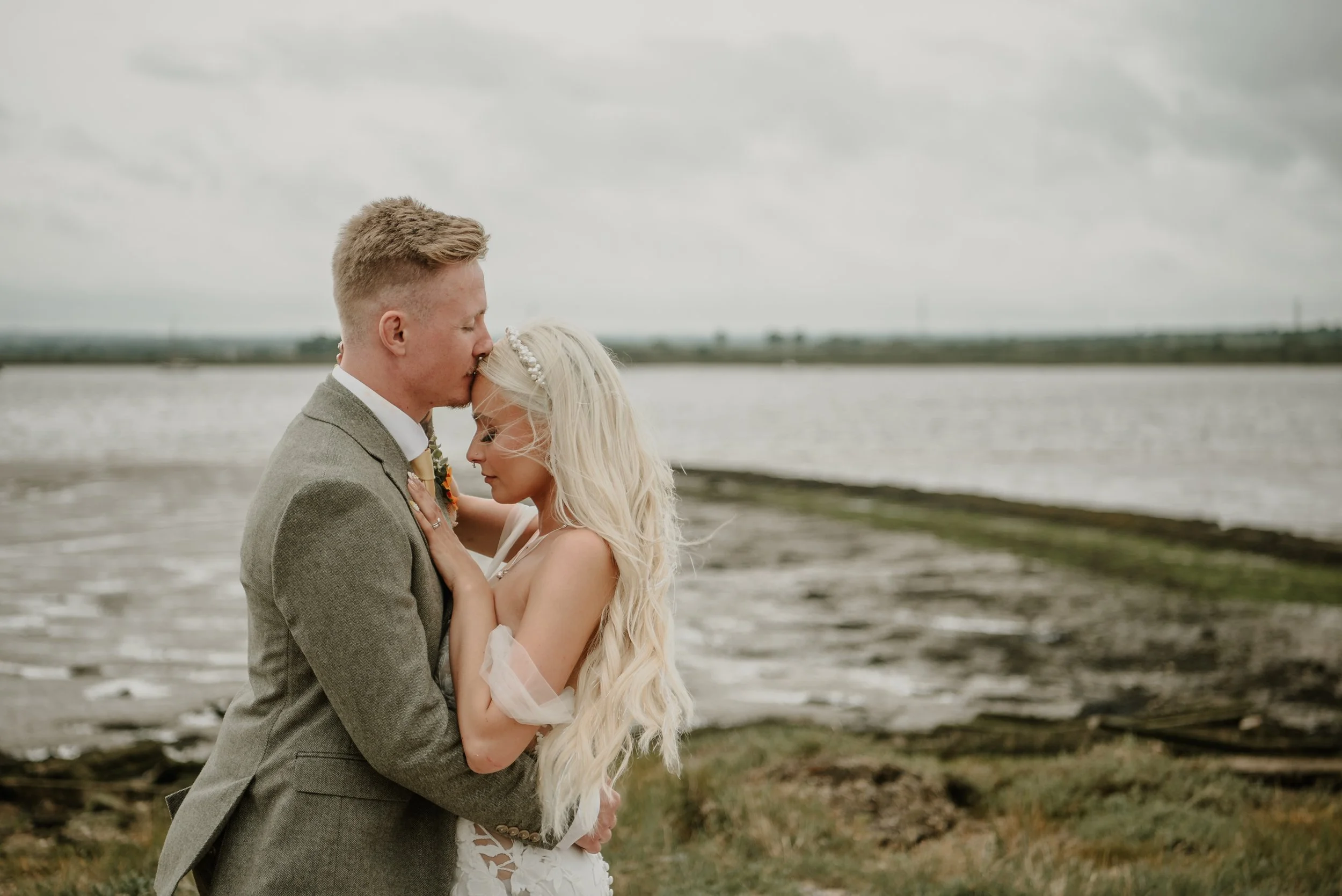Groom kissing bride's forward at the coast by the Ferry House