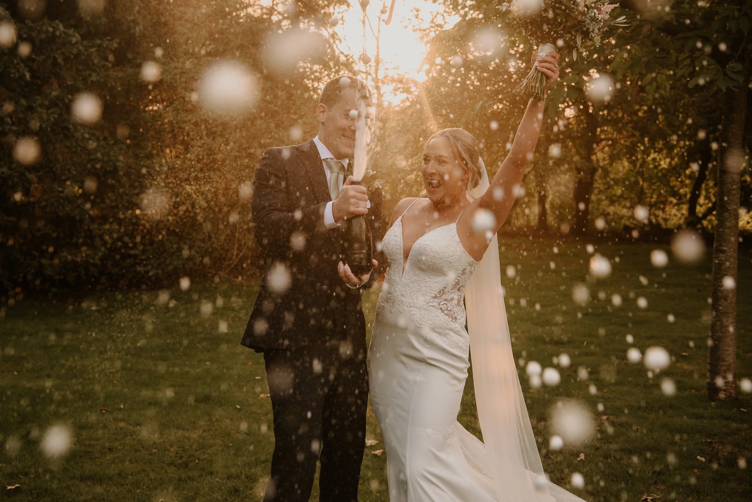 bride and groom spraying champnge towards the camera at Hayne House.