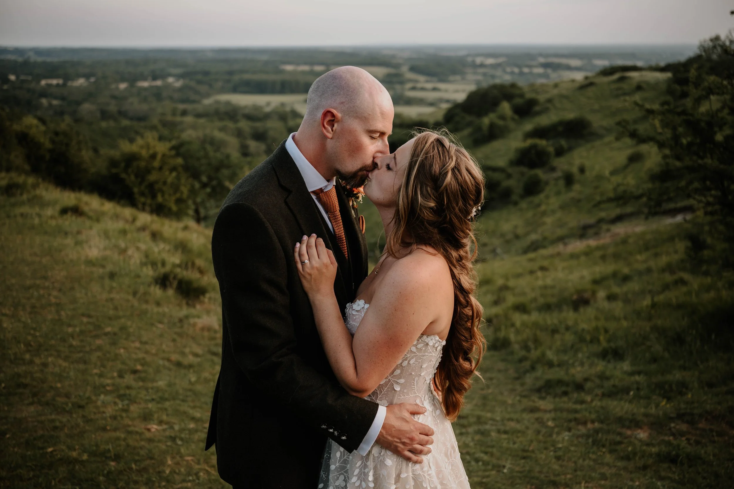 bride and groom kissing with the Wye Downs behind them.