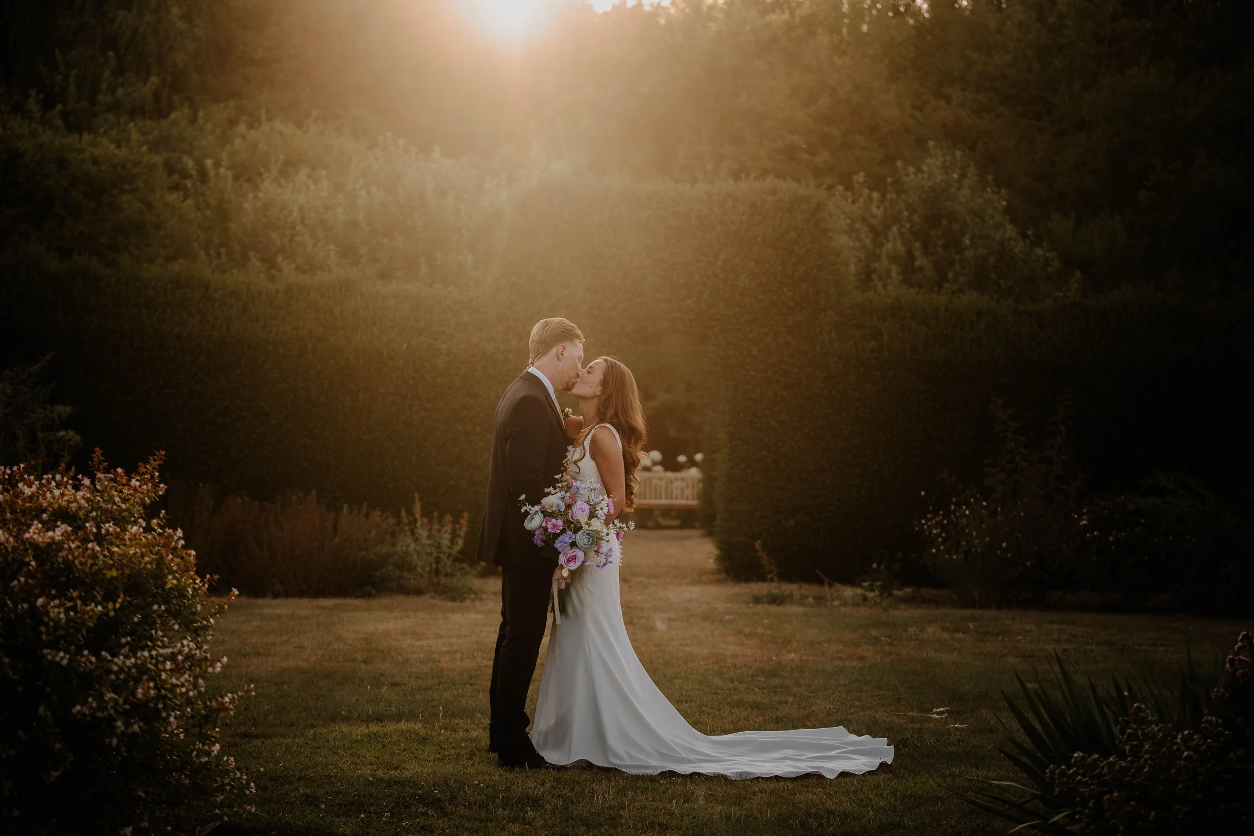 bride and groom kissing at sunset in the Gardens at Yalding