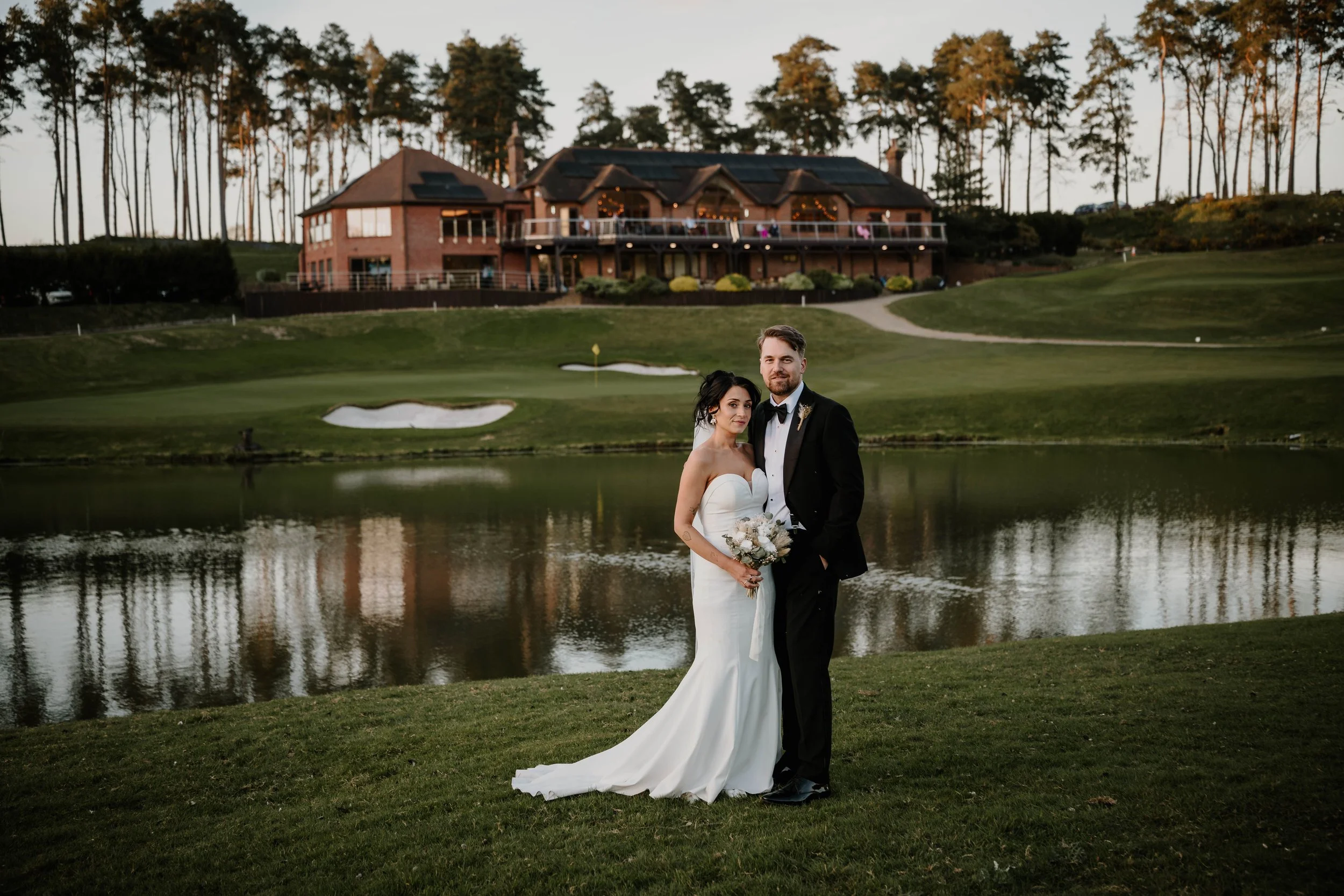 Bride and groom looking at camera with the westerham golf club building behind them