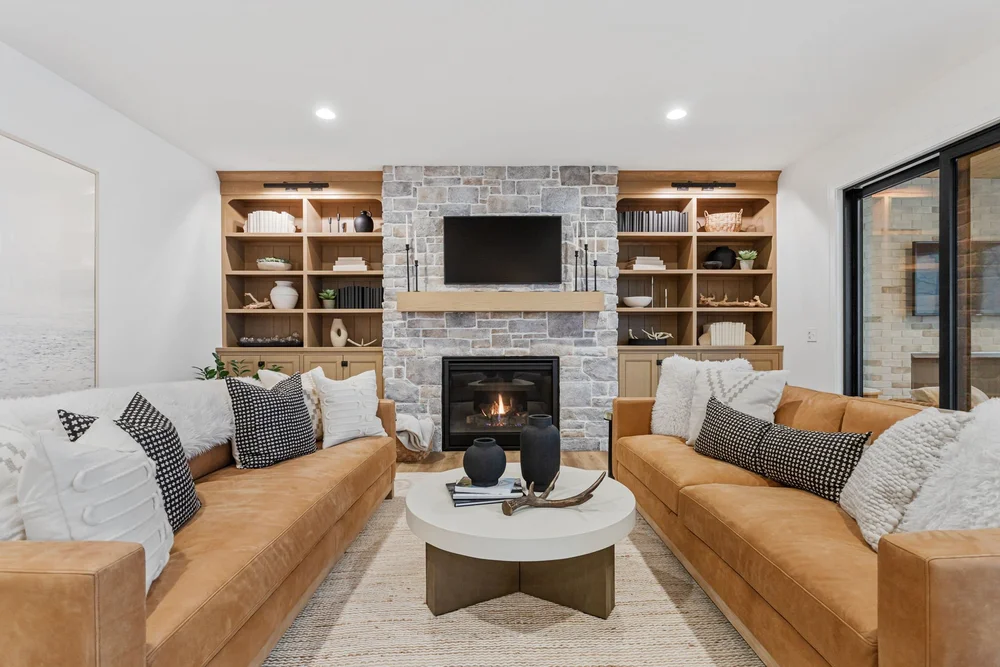 Living room with a stone fireplace and tan sofas at Pigeon Lake Luxury