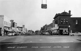 Historical black-and-white photo of Main Street with old storefronts and buildings