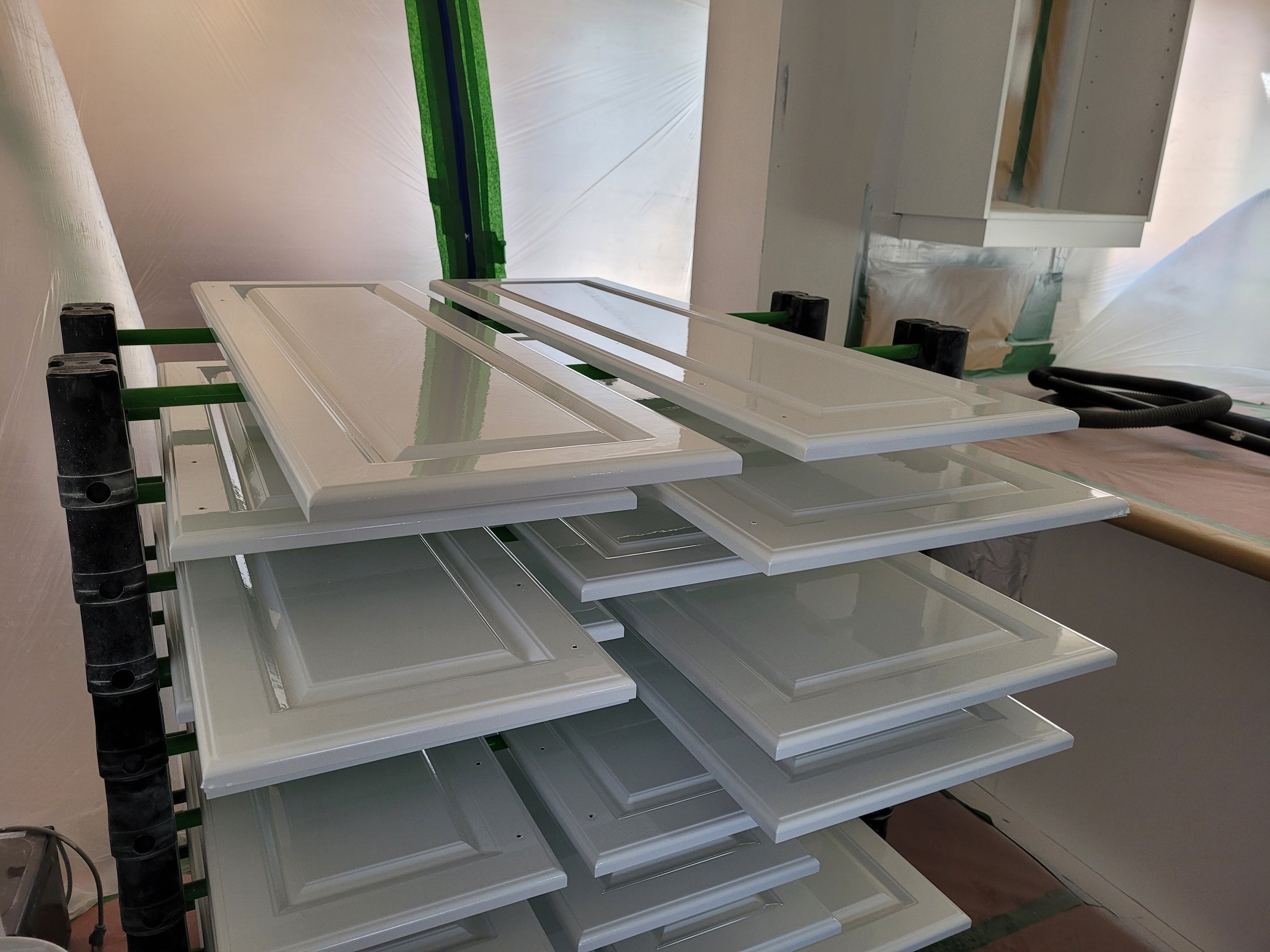 Portes d'armoires de cuisine fraîchement peintes au fusil séchant sur un rack dans la chambre à peinture ventilée