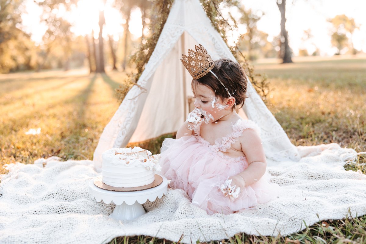 Baby girl in pink tulle dress eating birthday cake