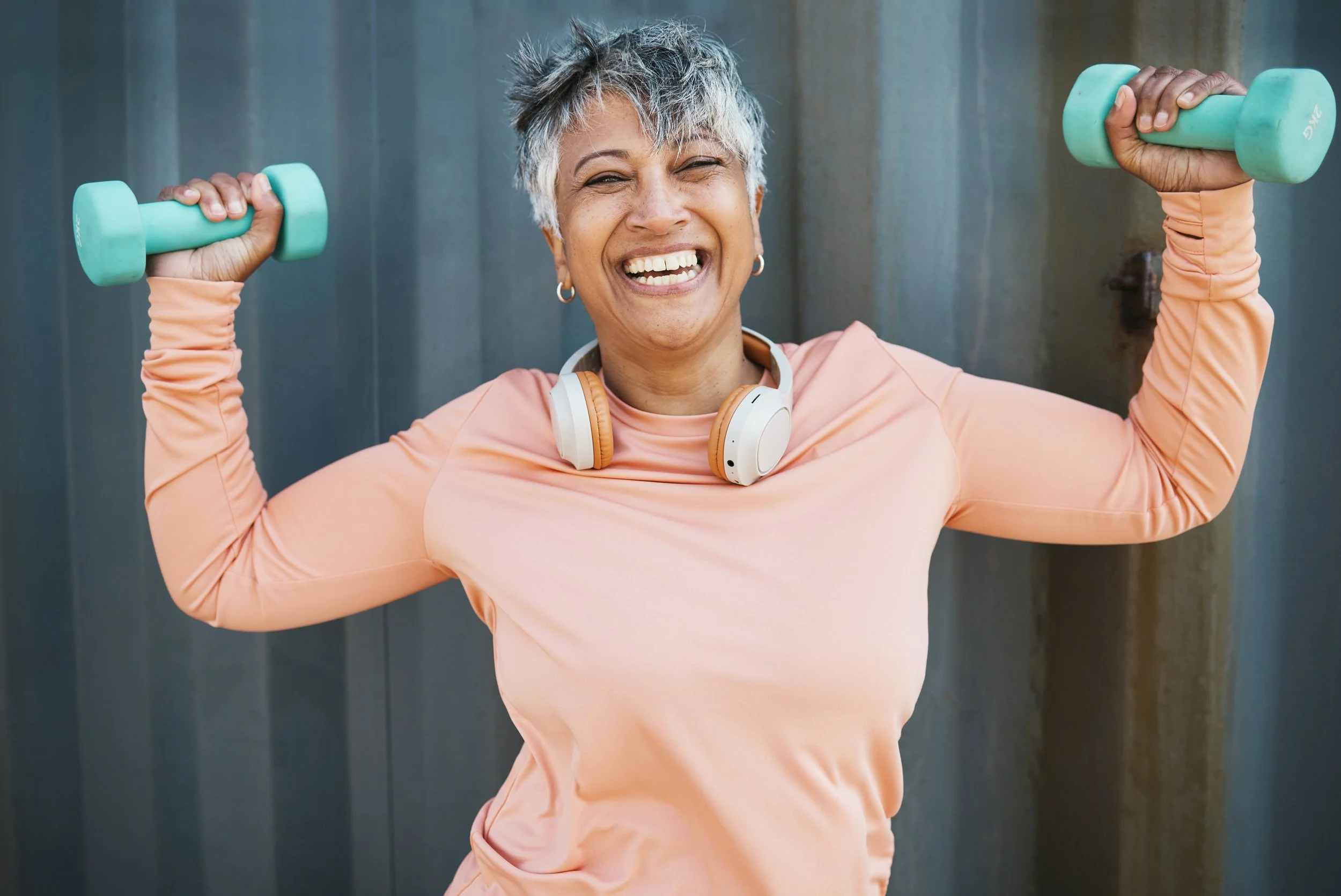 Portrait of an elderly woman holding dumbbells, representing fitness, strength training, and healthy aging through regular exercise and weightlifting for improved muscle and overall wellness.