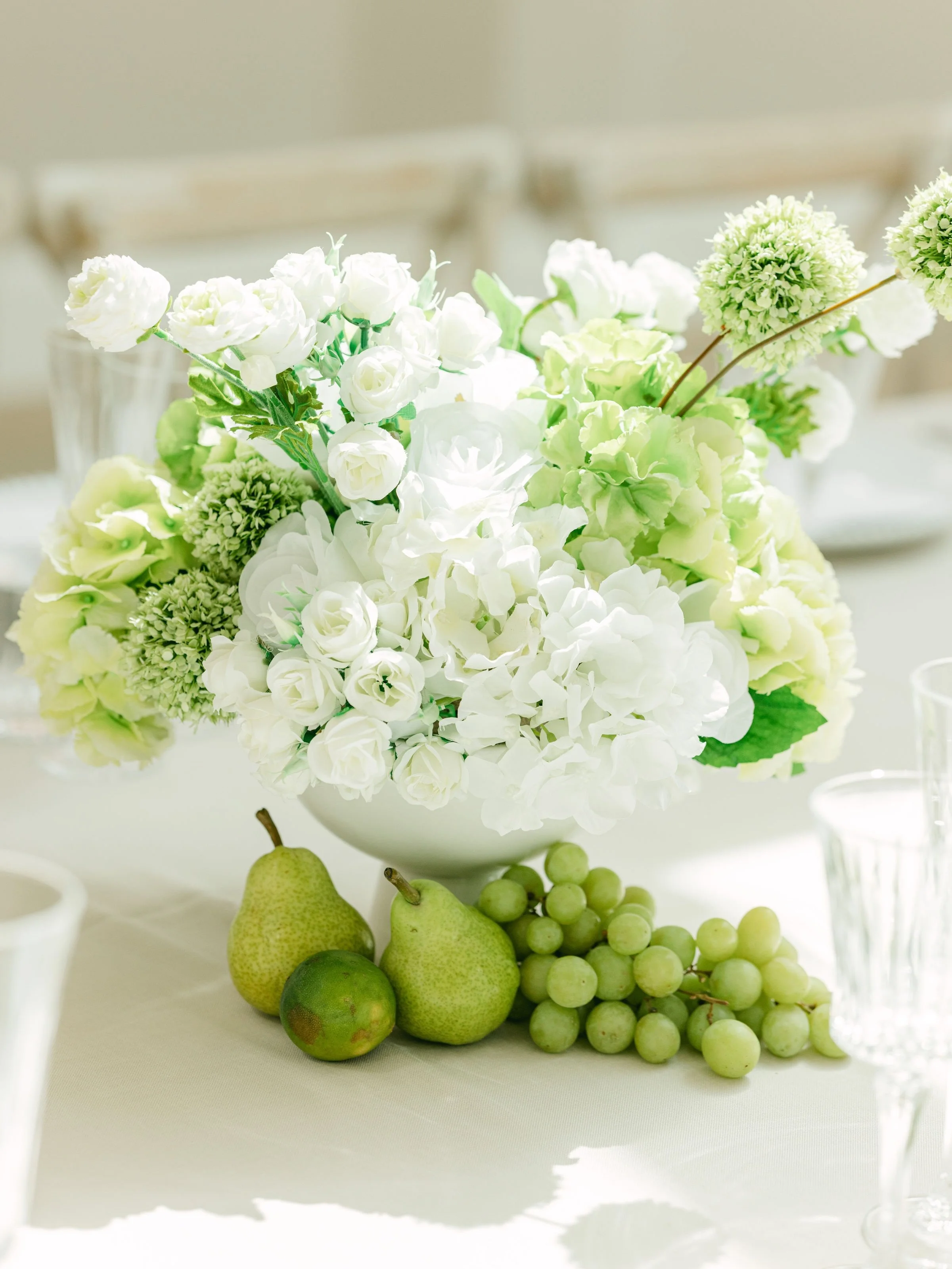 Green Hydrangea &amp; Rose 

A gorgeous arrangement of green hydrangeas, roses, ranunculus and alliums presented in an elegant ceramic footed vase. 

Beautifully styled with fresh fruits, table lamps and soft pink tapered candles. 

We adore the fres