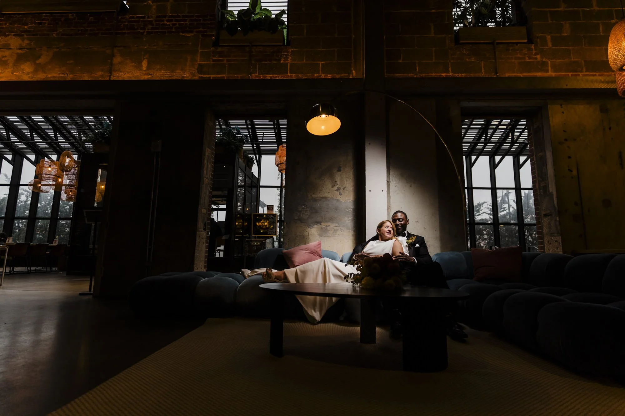 Wedding couple relaxing on a sofa in the warmly lit Asbury Hotel lounge