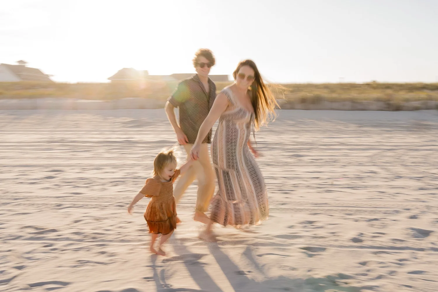 Family walking together on the beach at sunset