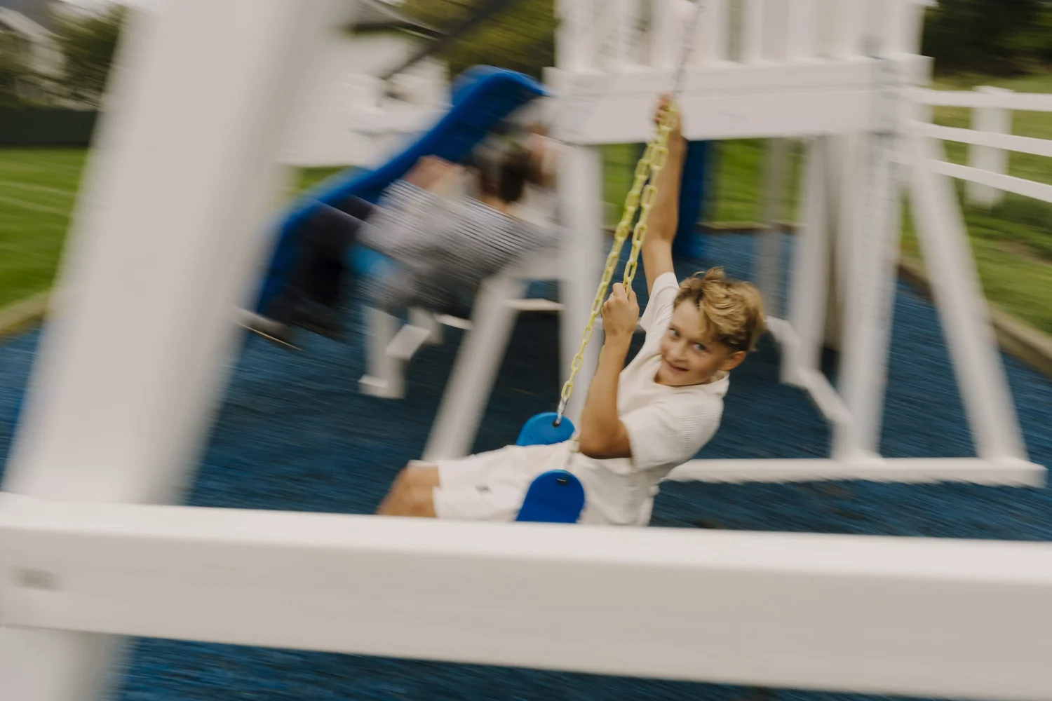 Blonde-haired boy on a blue swing with motion blur capturing the movement