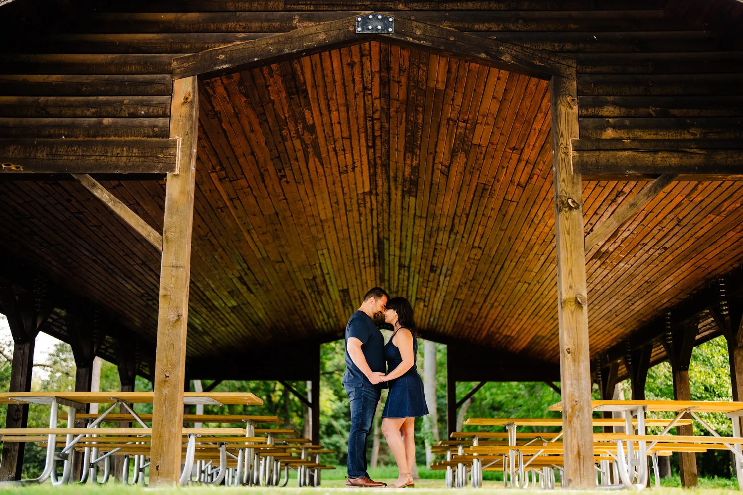 A couple embracing beneath a wooden pavilion.