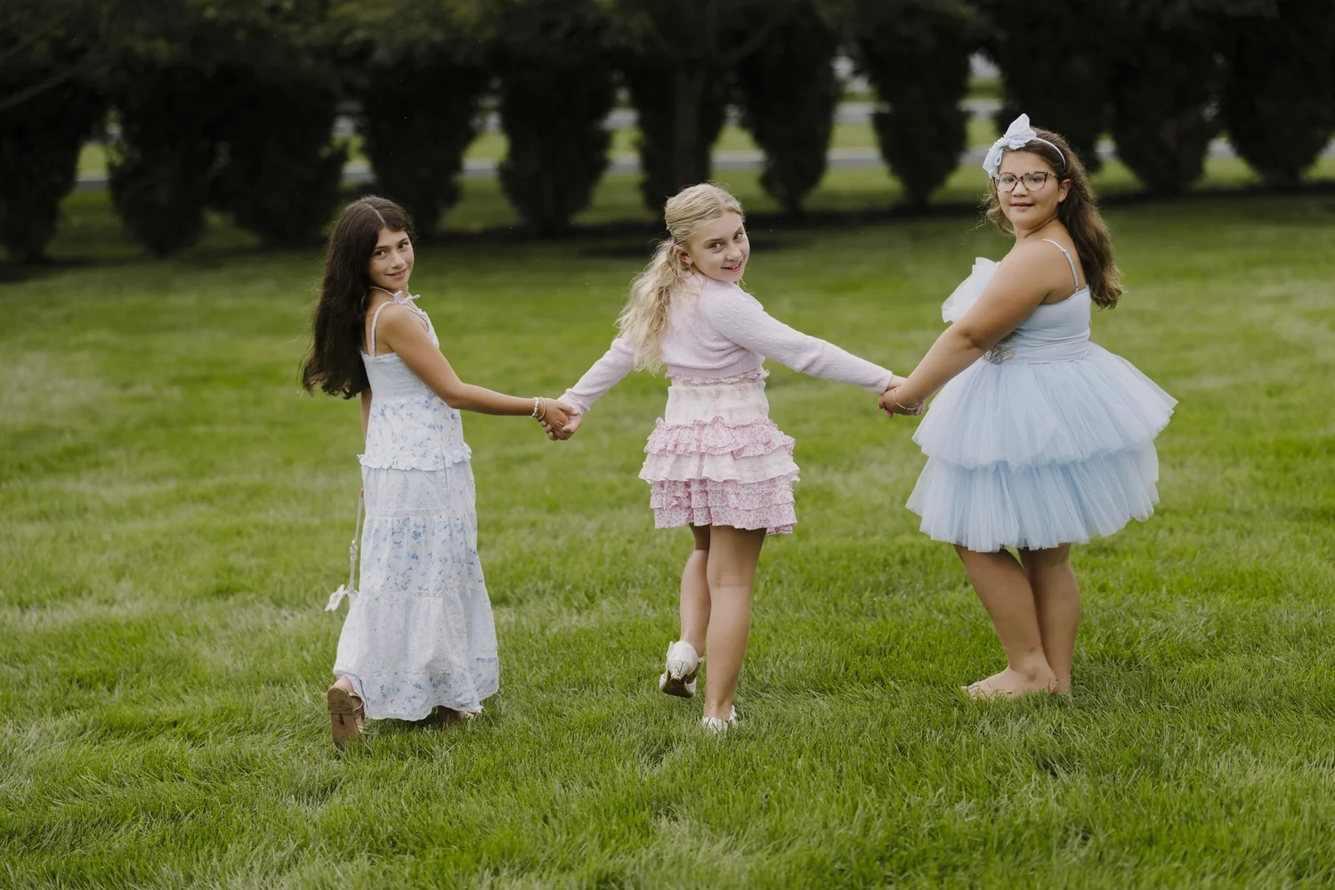 Three children holding hands on the lawn at the Holmdel celebration